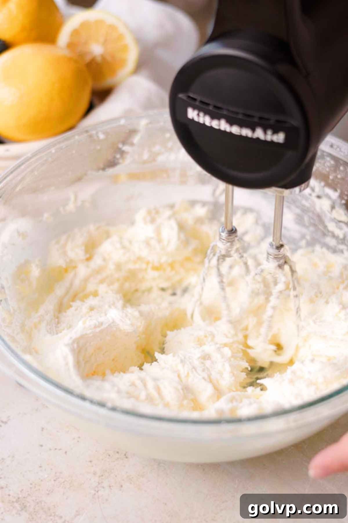 Beating softened unsalted butter and powdered sugar in a large glass bowl with an electric mixer until very creamy and fluffy.
