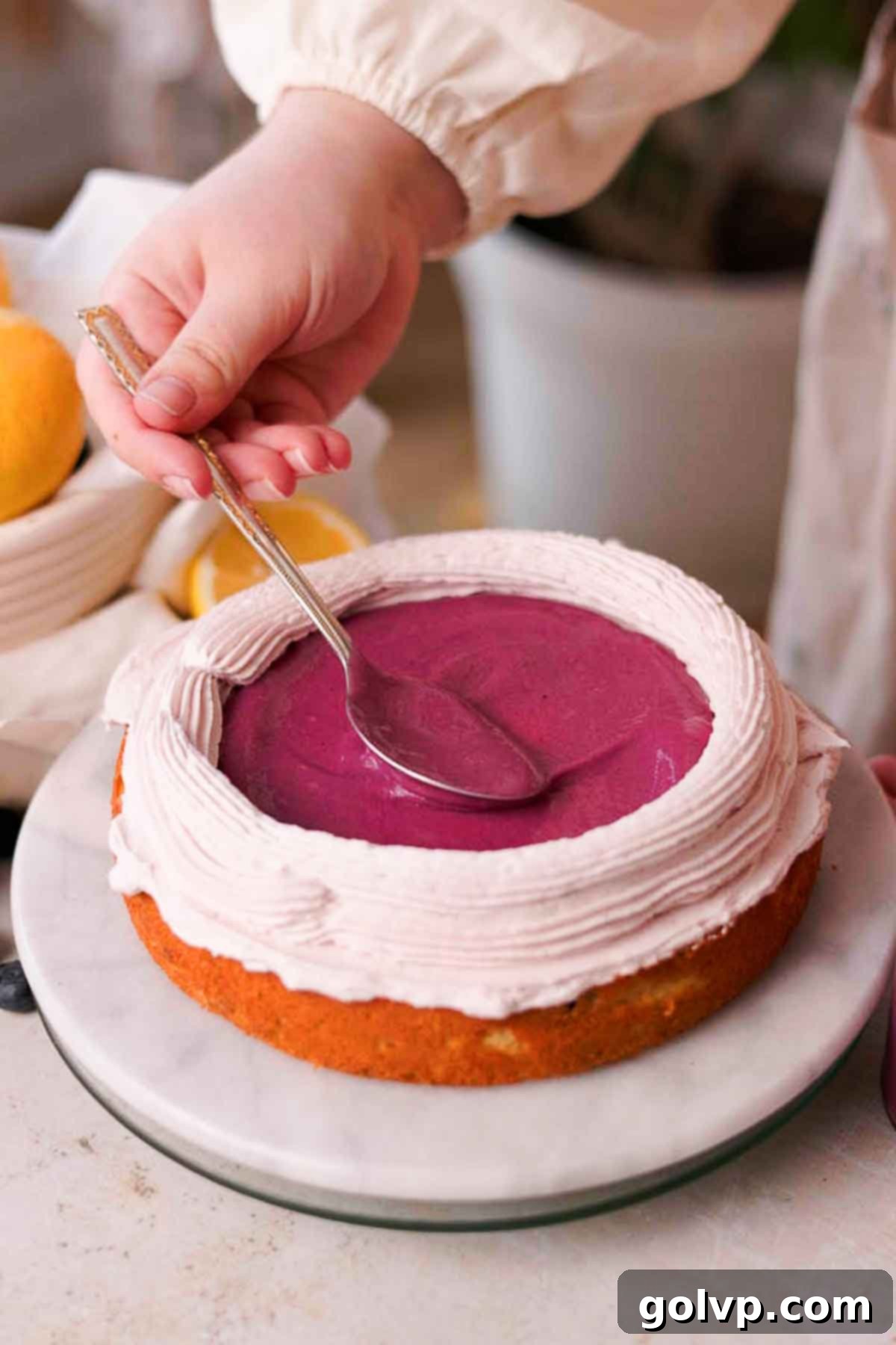 Filling the middle of a cake layer with a generous amount of rich blueberry curd, surrounded by a piped frosting border.