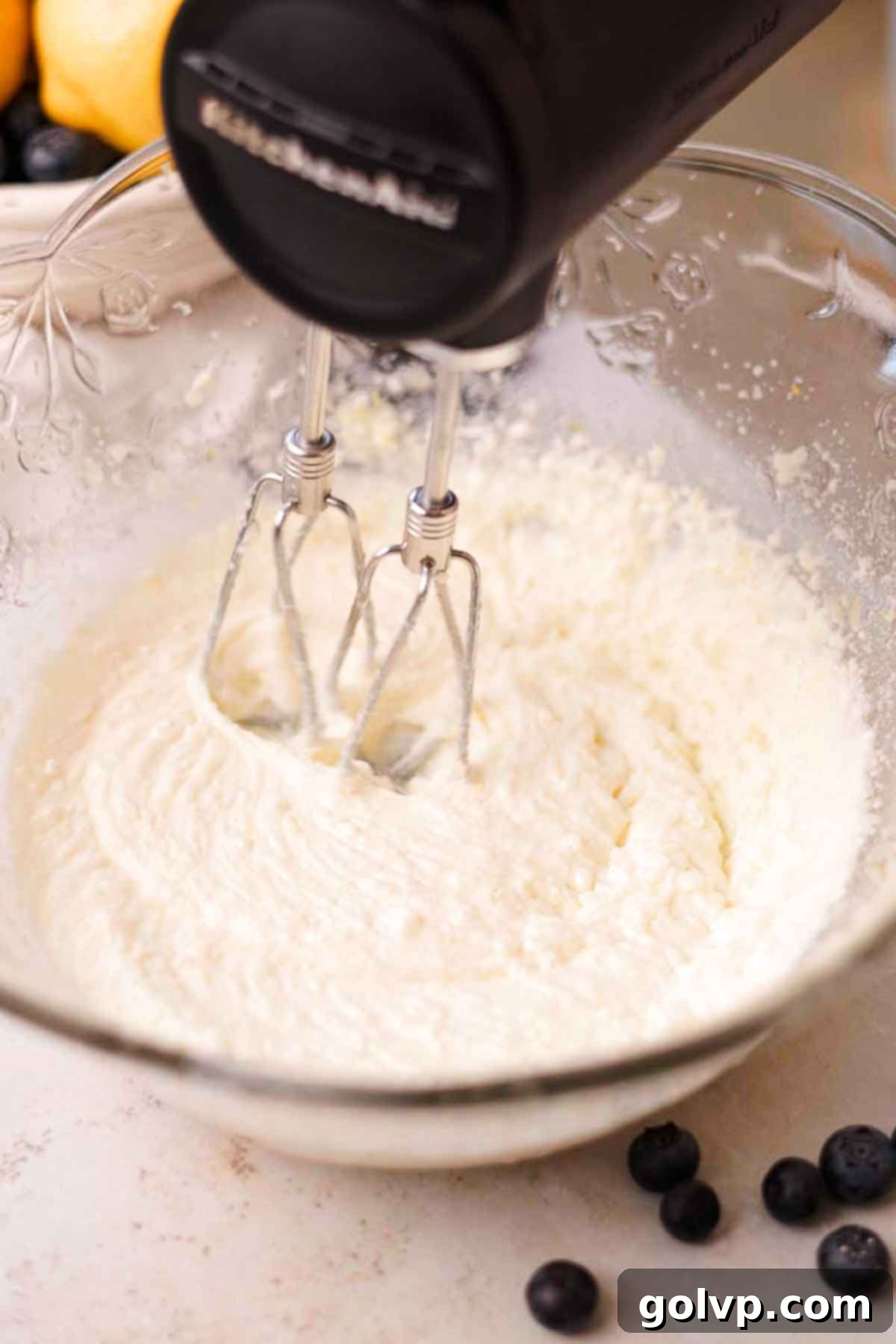 Beating softened butter, vegetable oil, and lemon-infused sugar in a glass bowl with an electric mixer until light and creamy.