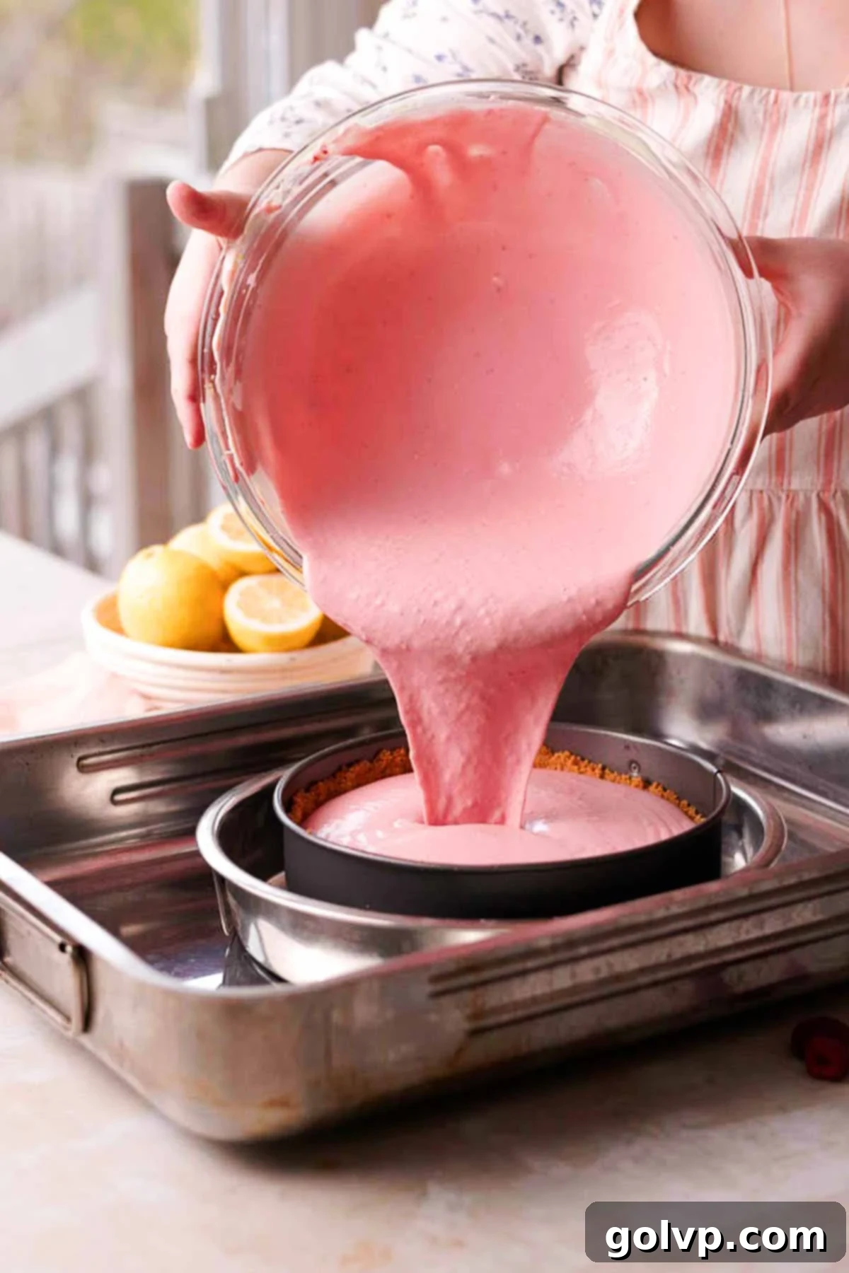 pouring pink cheesecake batter into prepared cheesecake crust
