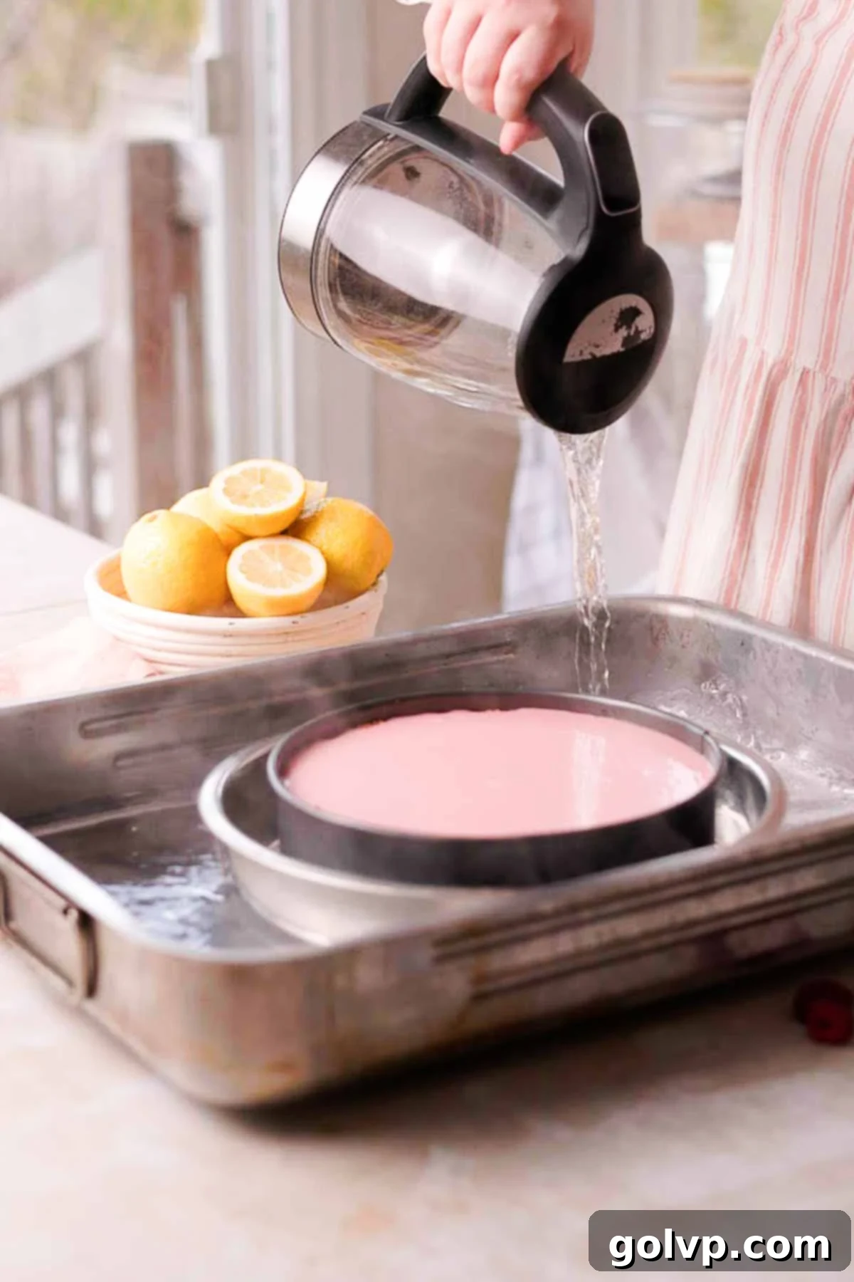 pouring boiling water into hot water bath with lemon raspberry cheesecake