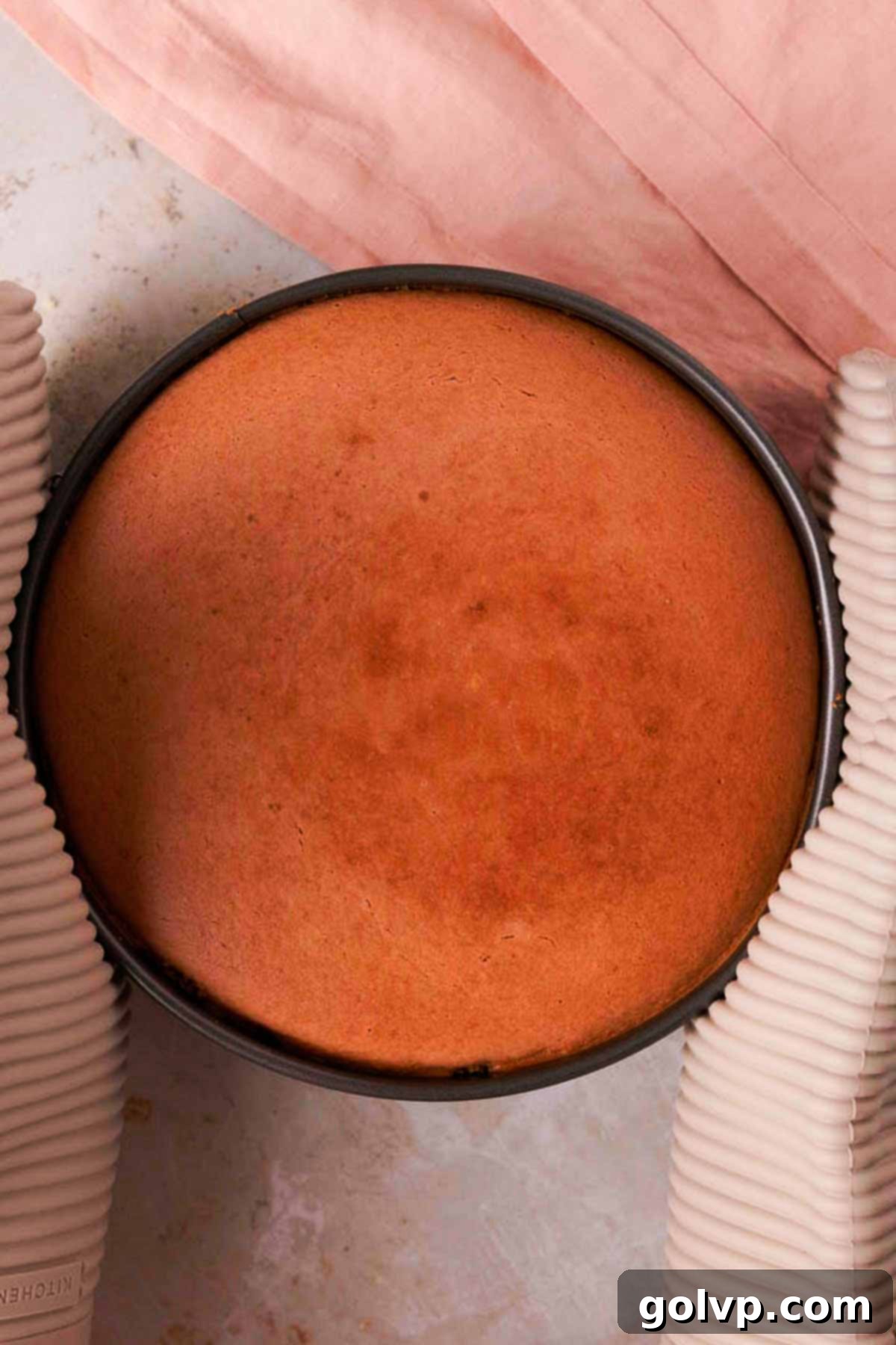 holding baked cheesecake with oven mitts