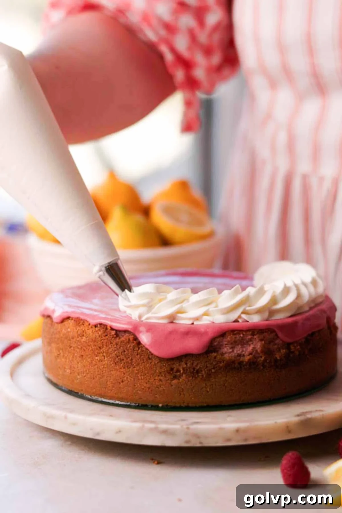 piping whipped cream on top of cheesecake covered in raspberry curd