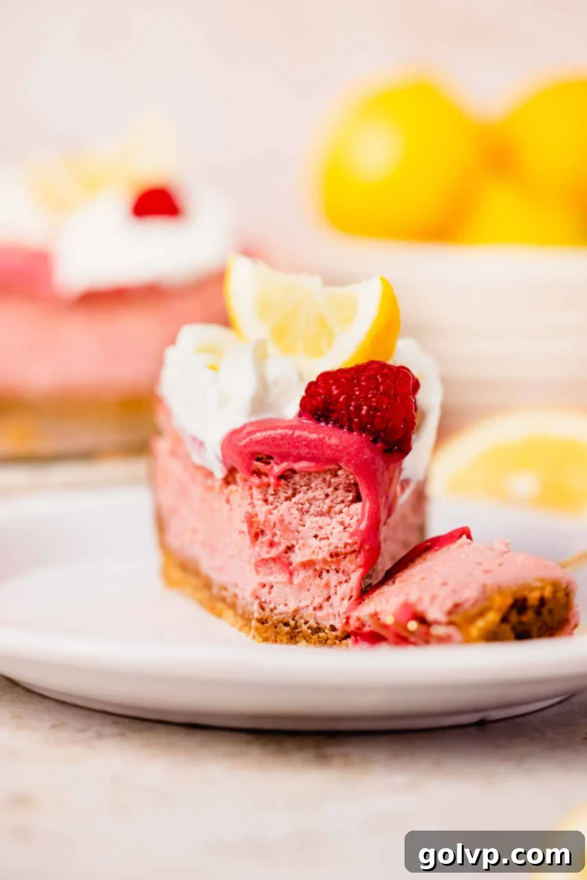 slice of lemon raspberry cheesecake with fork taking a bite