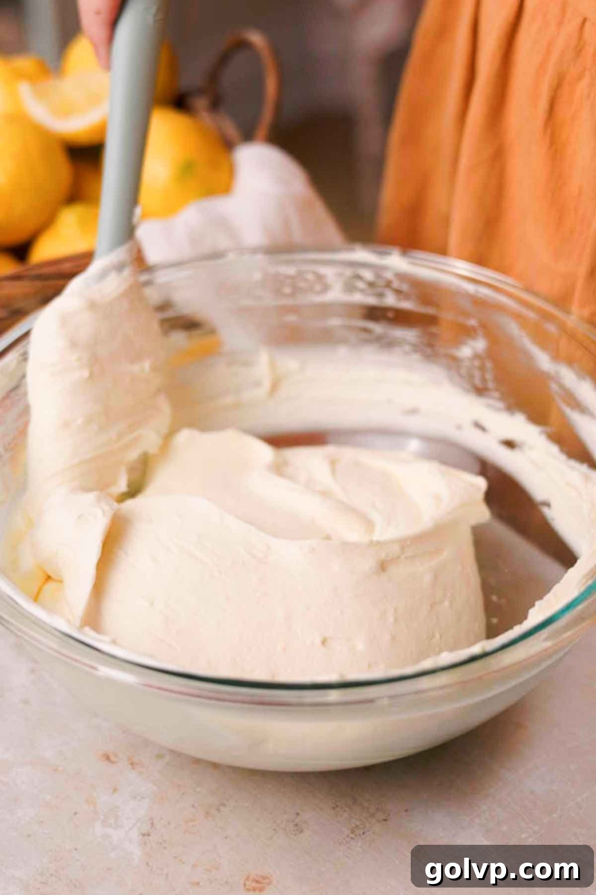 folding lemon cheesecake filling with a silicone spatula in a large glass bowl