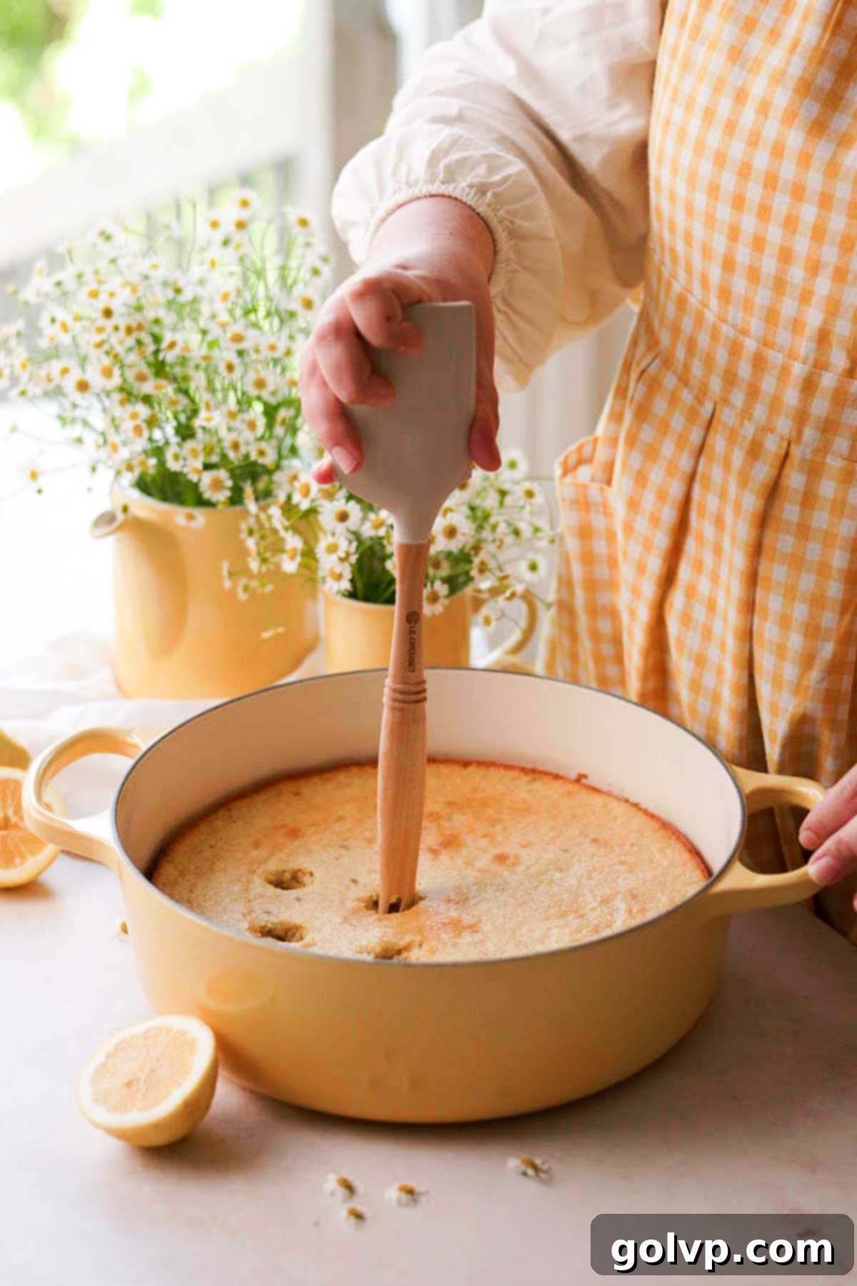Gently poking holes into the surface of the cooled, freshly baked lemon cake using the back of a spatula.