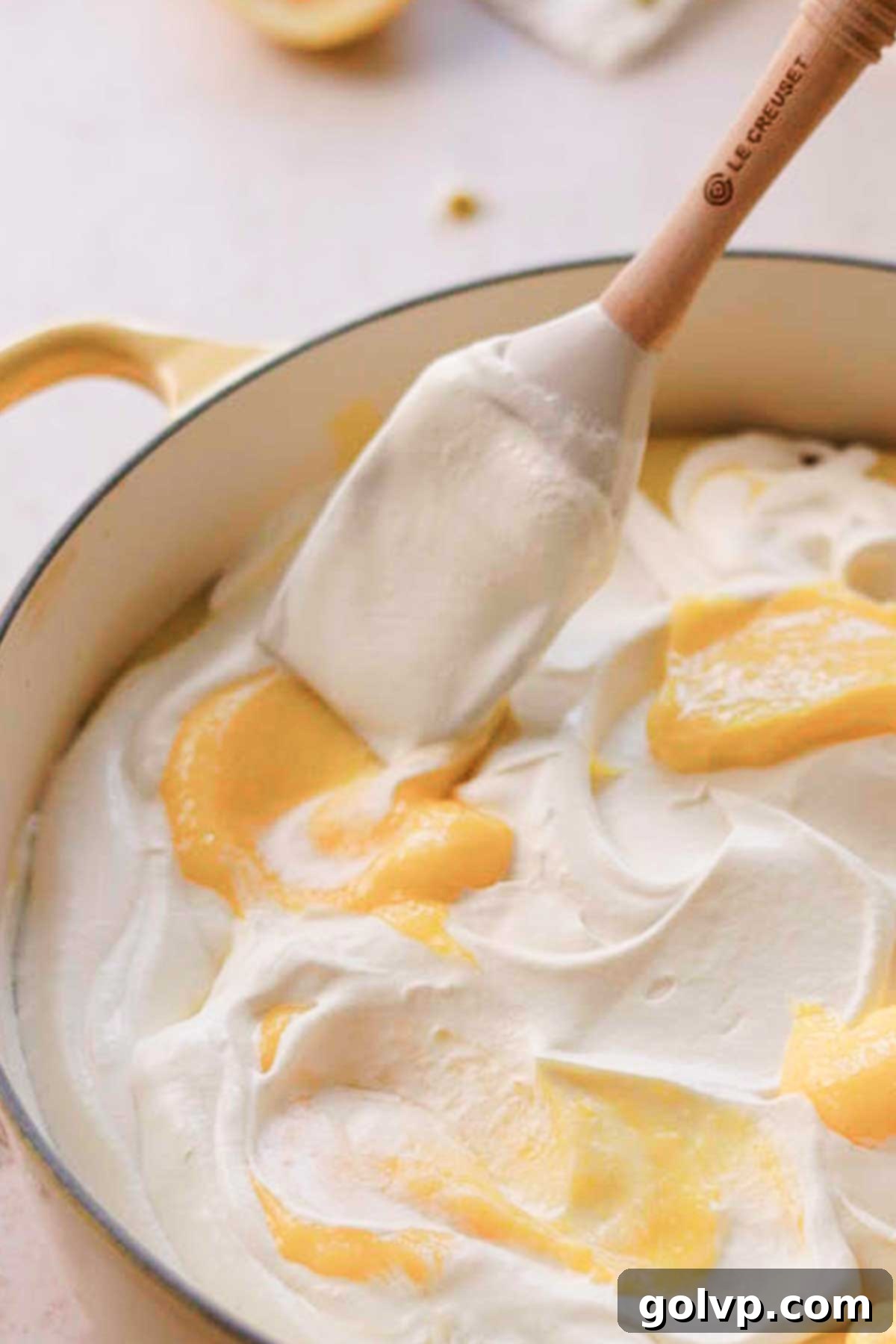 The final touch: artfully swirling the reserved lemon curd on top of the whipped cream with a spatula, creating a beautiful marble effect.