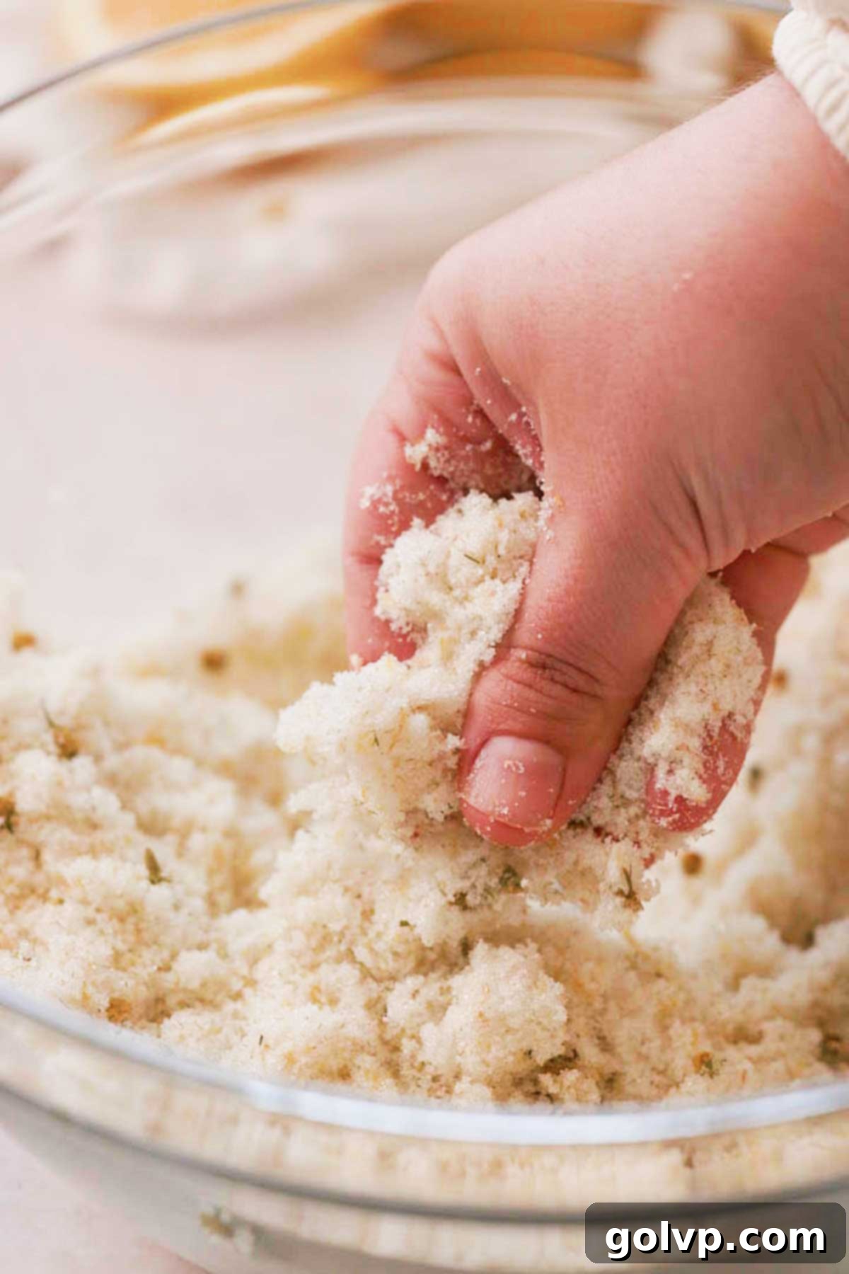 Fingers gently rubbing granulated sugar, fresh lemon zest, and chamomile tea together to release their fragrant oils, a crucial first step for the lemon cake batter.