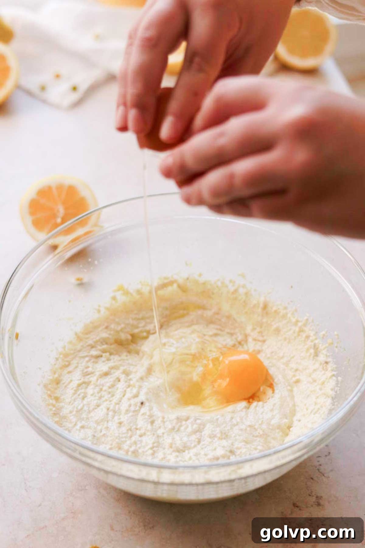 Adding eggs one at a time into the creamy lemon cake batter, ensuring each is fully incorporated before the next addition to maintain emulsion.