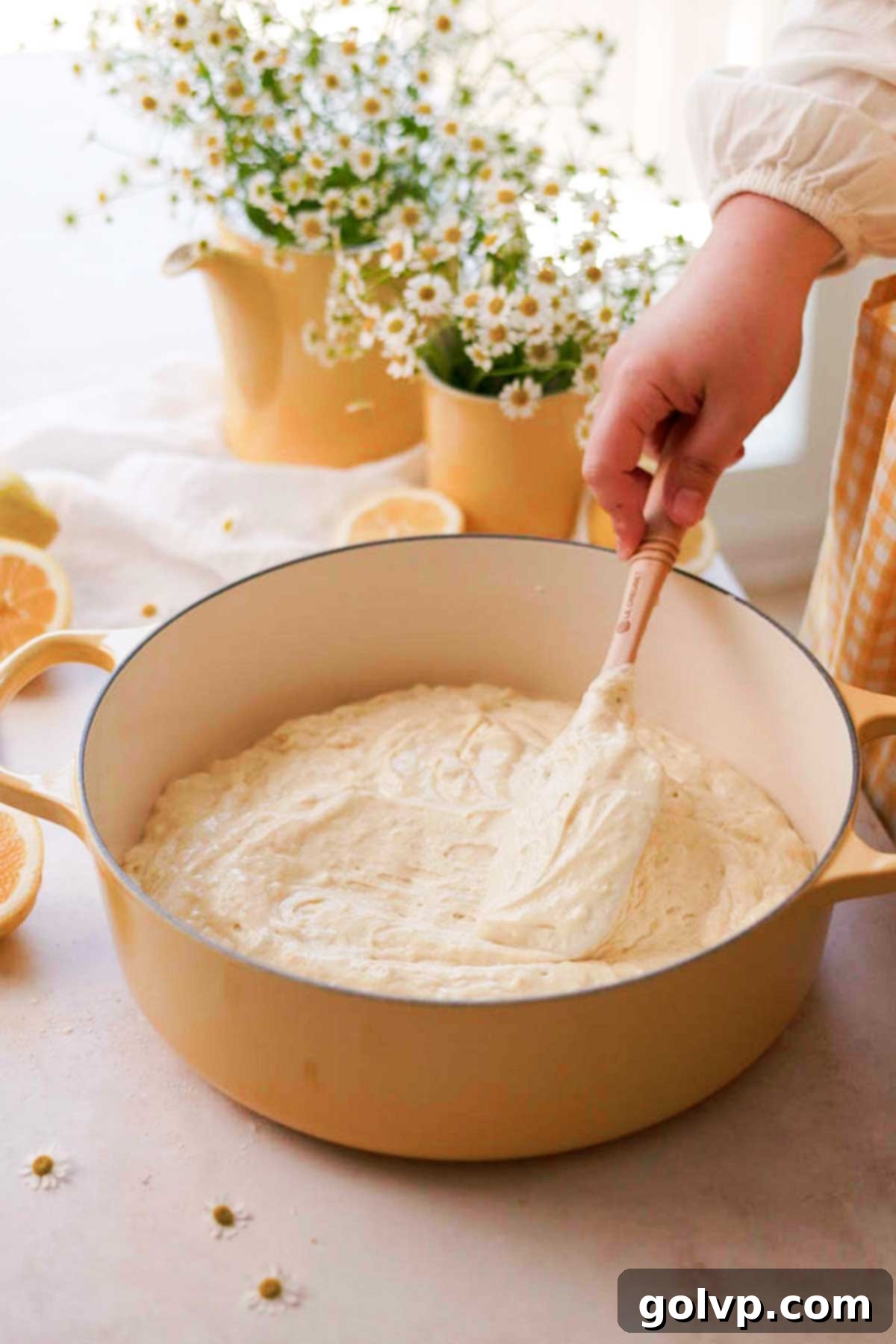 Spreading the smooth lemon cake batter evenly into a greased Dutch oven, ready for baking.