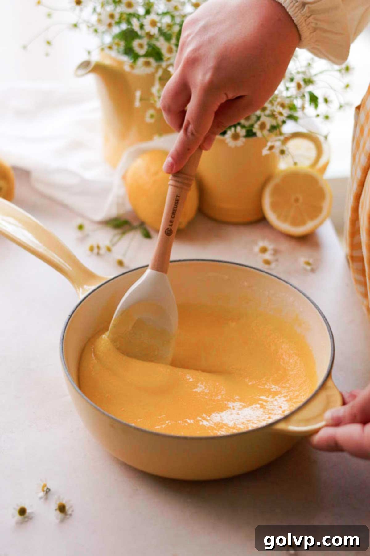 Whisking egg yolks and granulated sugar together in a saucepan to create the creamy base for homemade lemon curd.