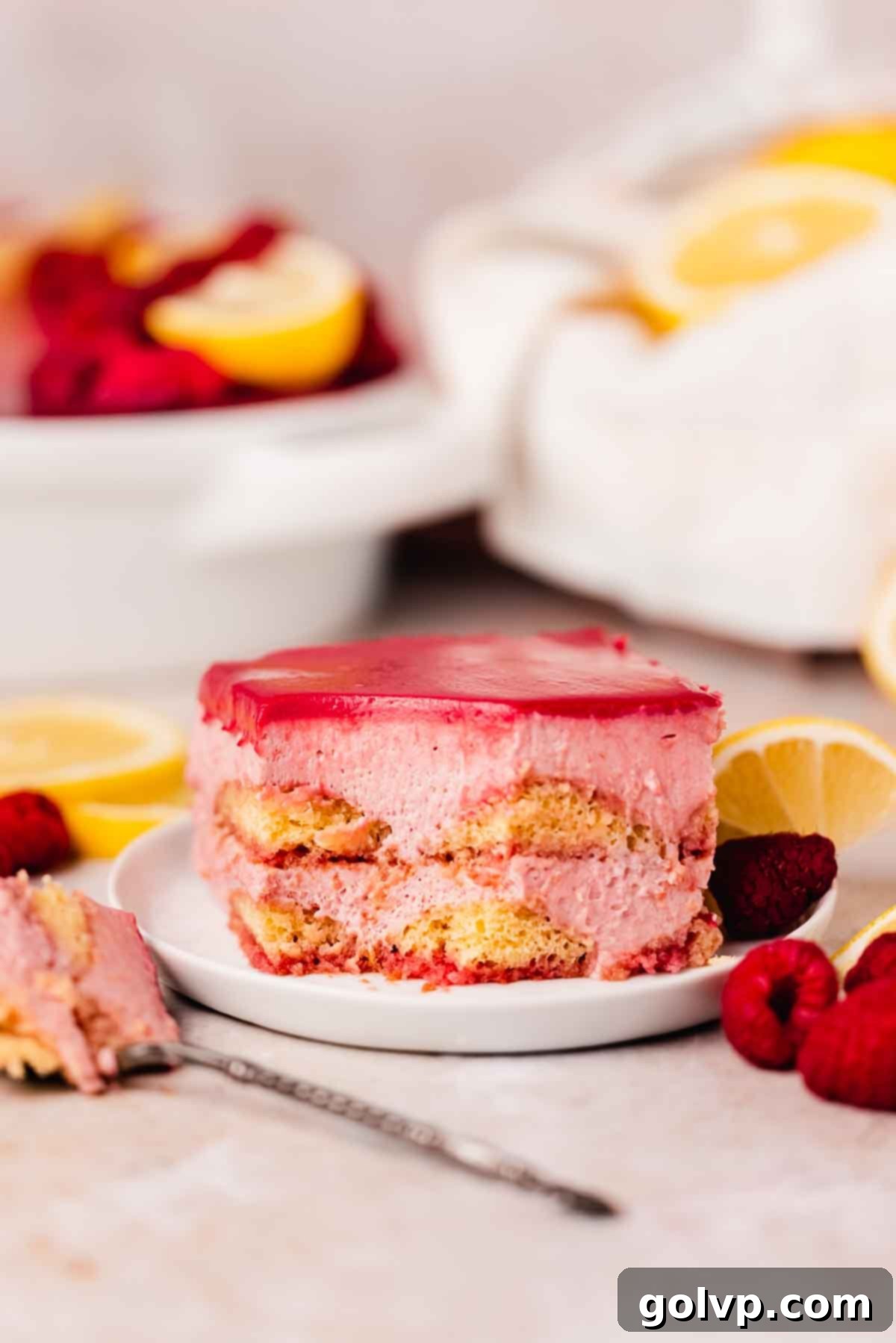 raspberry curd tiramisu slice on small plate with fresh raspberries