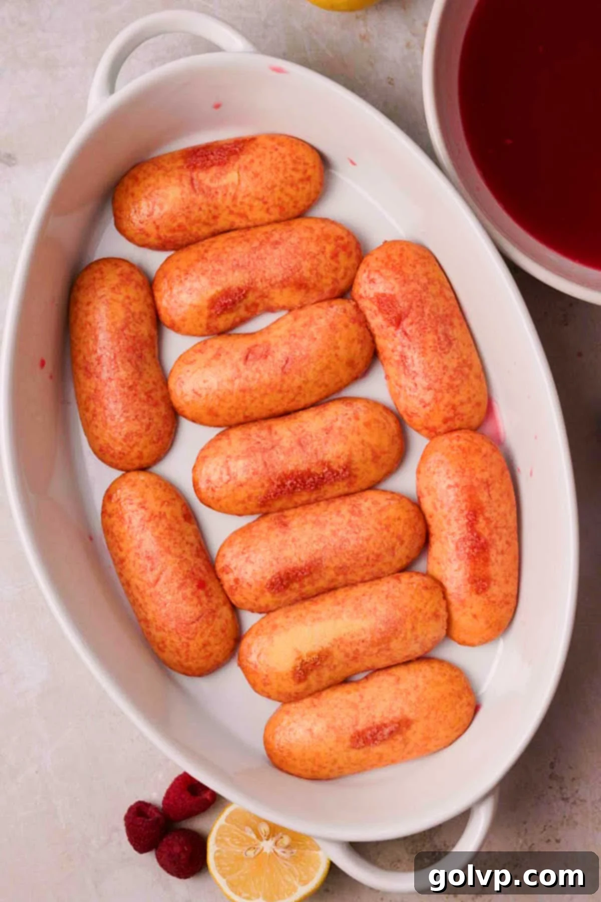 layering syrup soaked ladyfingers in a ceramic casserole dish