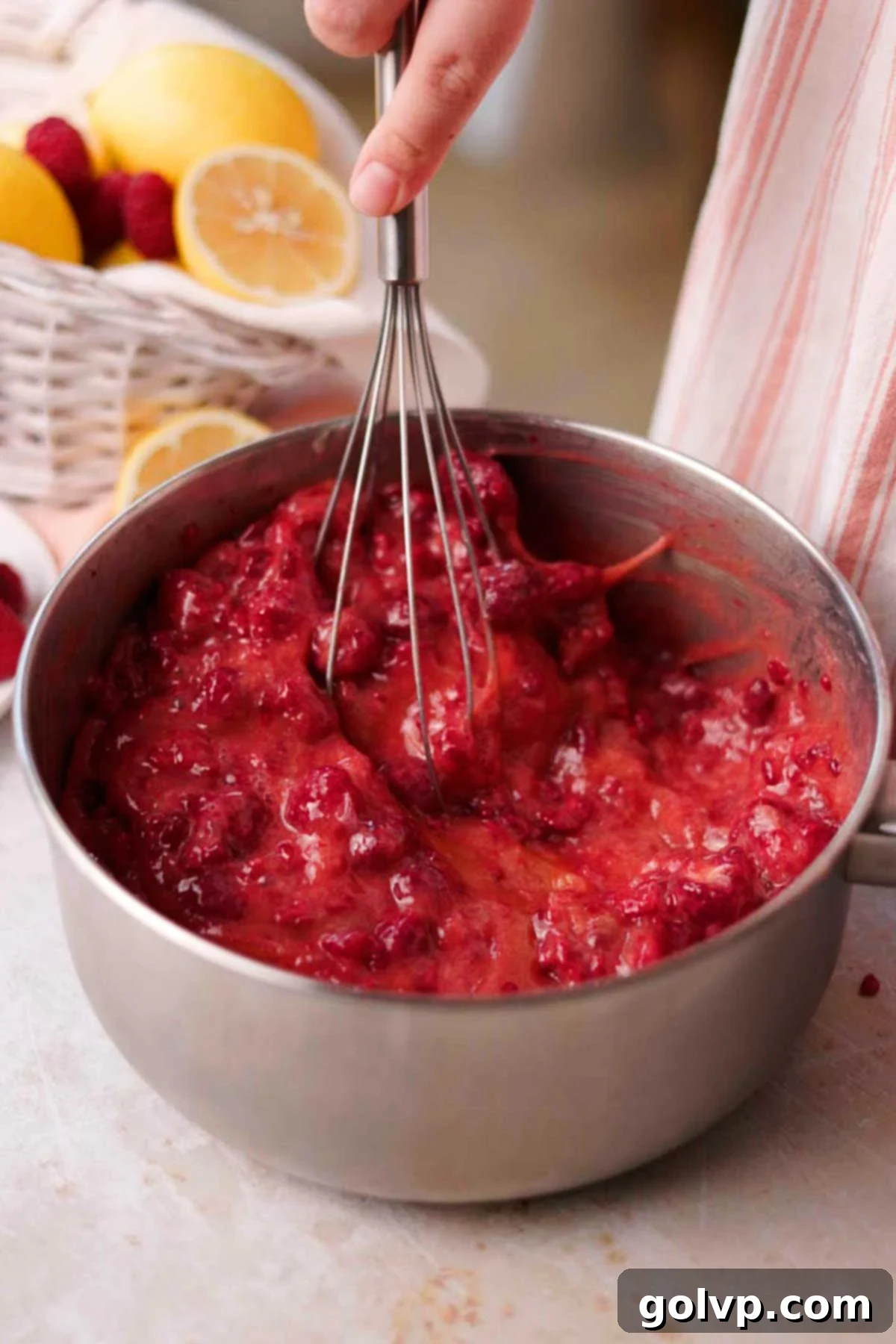 stirring uncooked raspberry curd with a whisk