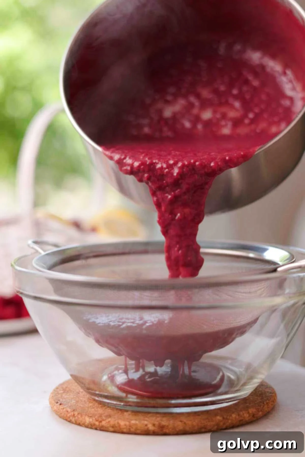 straining raspberry curd through a sieve