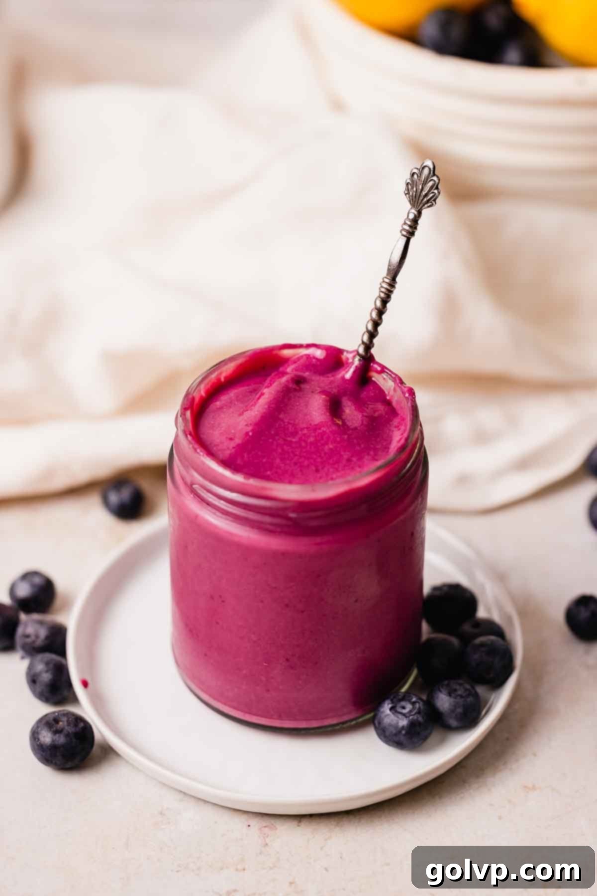 thick blueberry curd in jar with silver spoon