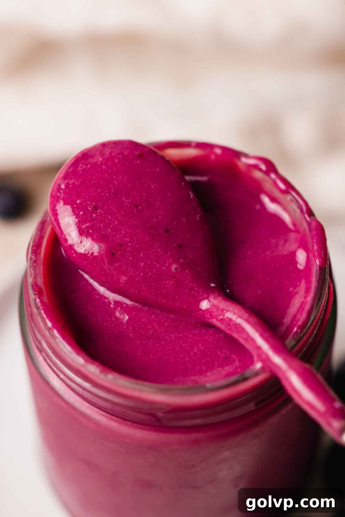 blueberry curd in jar with spoon resting on jar's rim