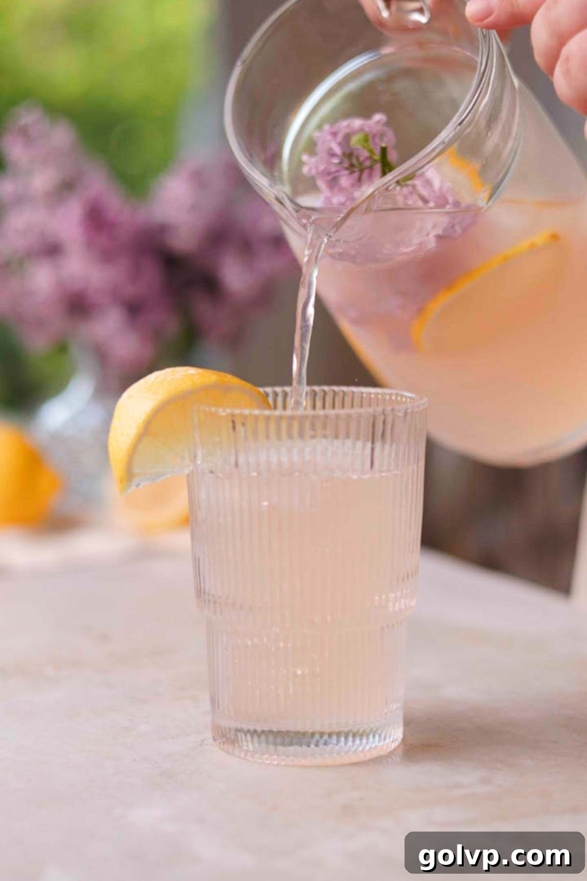 pouring lilac lemonade into a glass