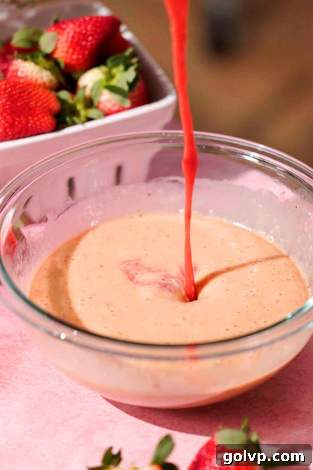 pouring strawberry sauce into bowl of whisked eggs