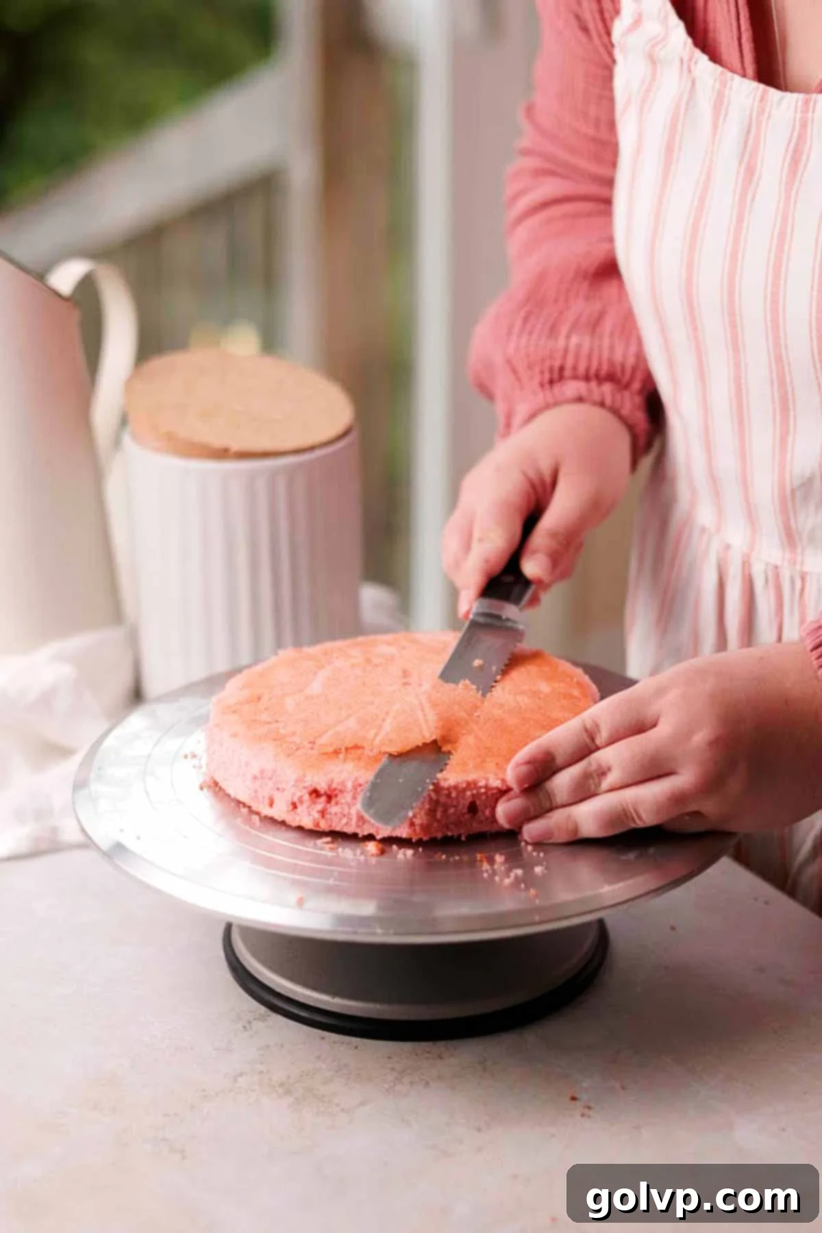 trimming the bottom of a baked pink velvet cake layer