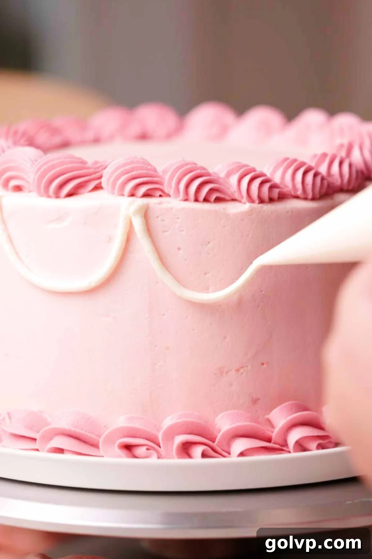 piping vintage white swoops onto side of pink birthday cake