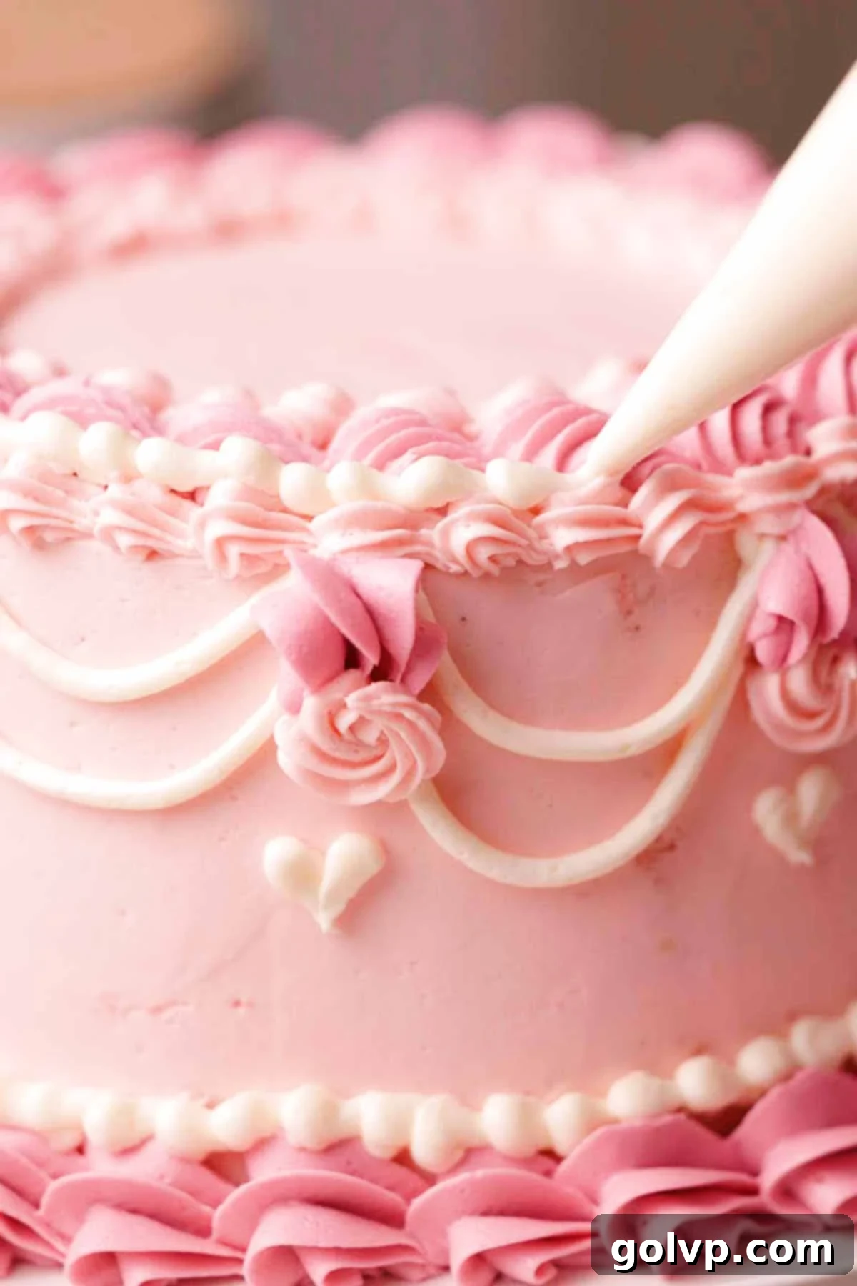 piping white beaded border on top edge of pink velvet cake
