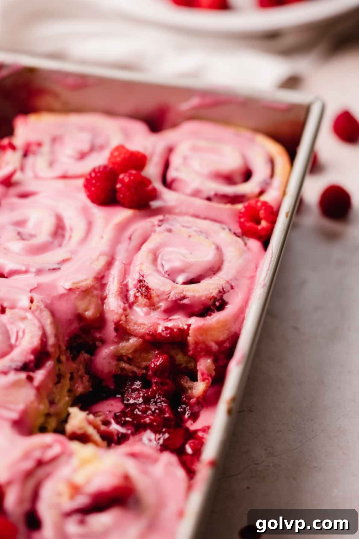raspberry rolls in pan with gooey filling at the bottom of the pan