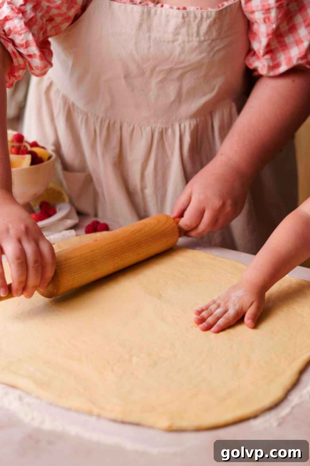 rolling out raspberry roll dough into a large rectangle with wood rolling pin