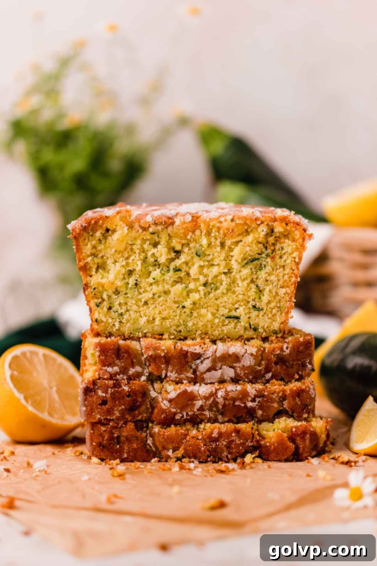 Slices of incredibly moist and tangy lemon zucchini bread stacked on top of each other, showcasing the perfect texture and golden-brown crust.