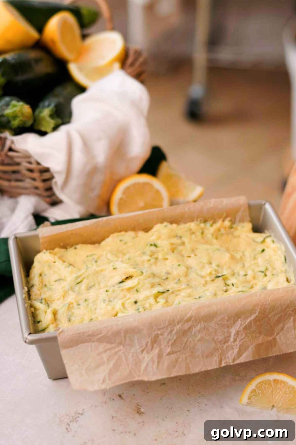 The smooth lemon zucchini batter expertly spread into a parchment-lined loaf pan, ready for baking.