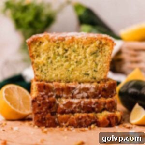 Slices of incredibly moist and tangy lemon zucchini bread stacked on top of each other, showcasing the perfect texture and golden-brown crust.