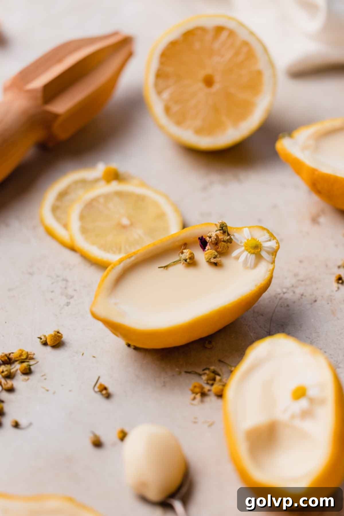 Lemon posset in a lemon rind, elegantly garnished with a delicate chamomile tea flower on top, highlighting the tea infusion.