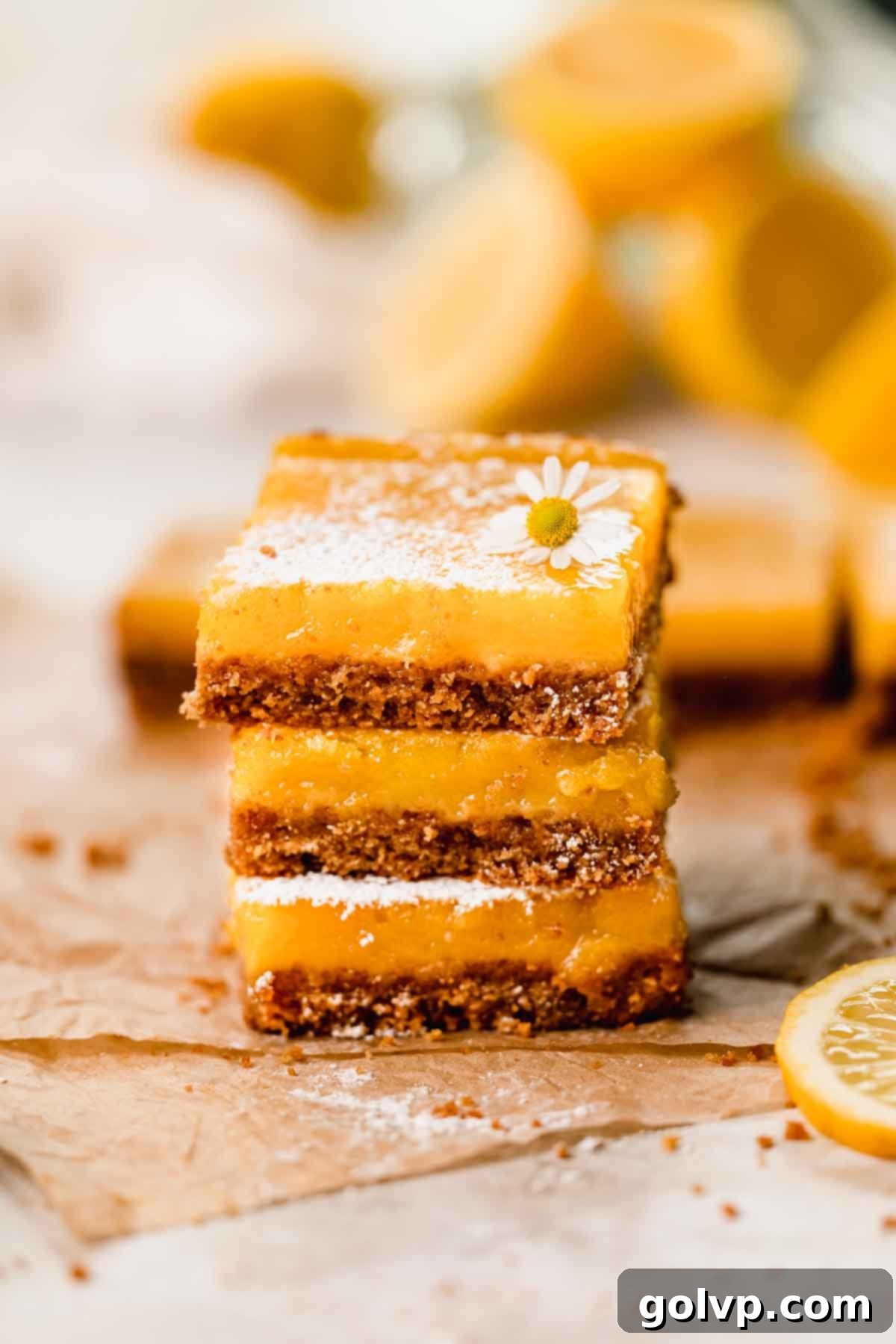 stacked lemon bars with graham cracker crust and powdered sugar