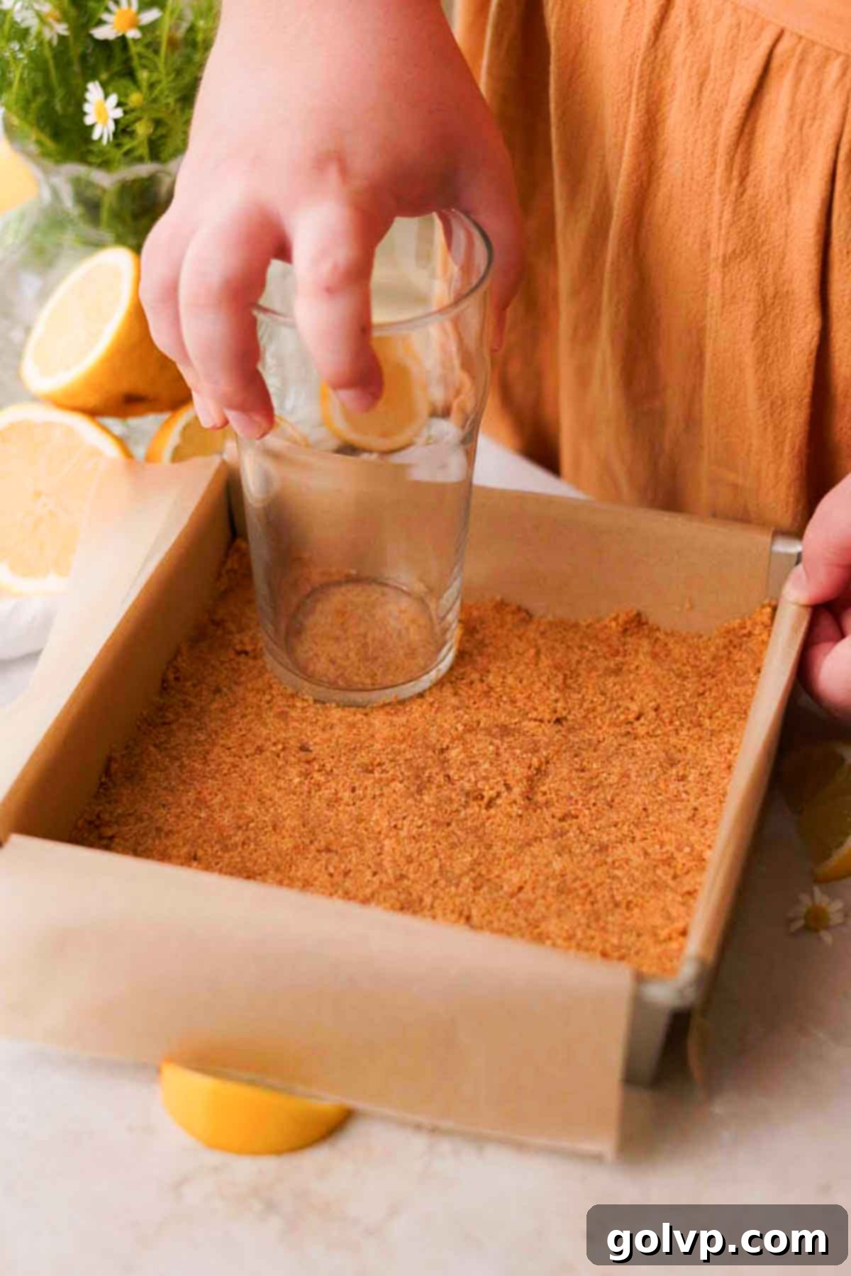 pressing graham cracker crust into the bottom of a baking pan