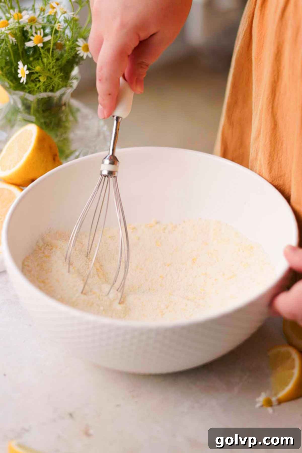 stirring sugar, lemon zest, and flour in a large bowl with a whisk