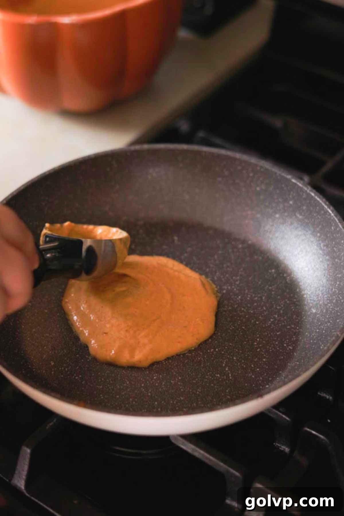 Step 1: Scooping pumpkin pancake batter into a greased pan