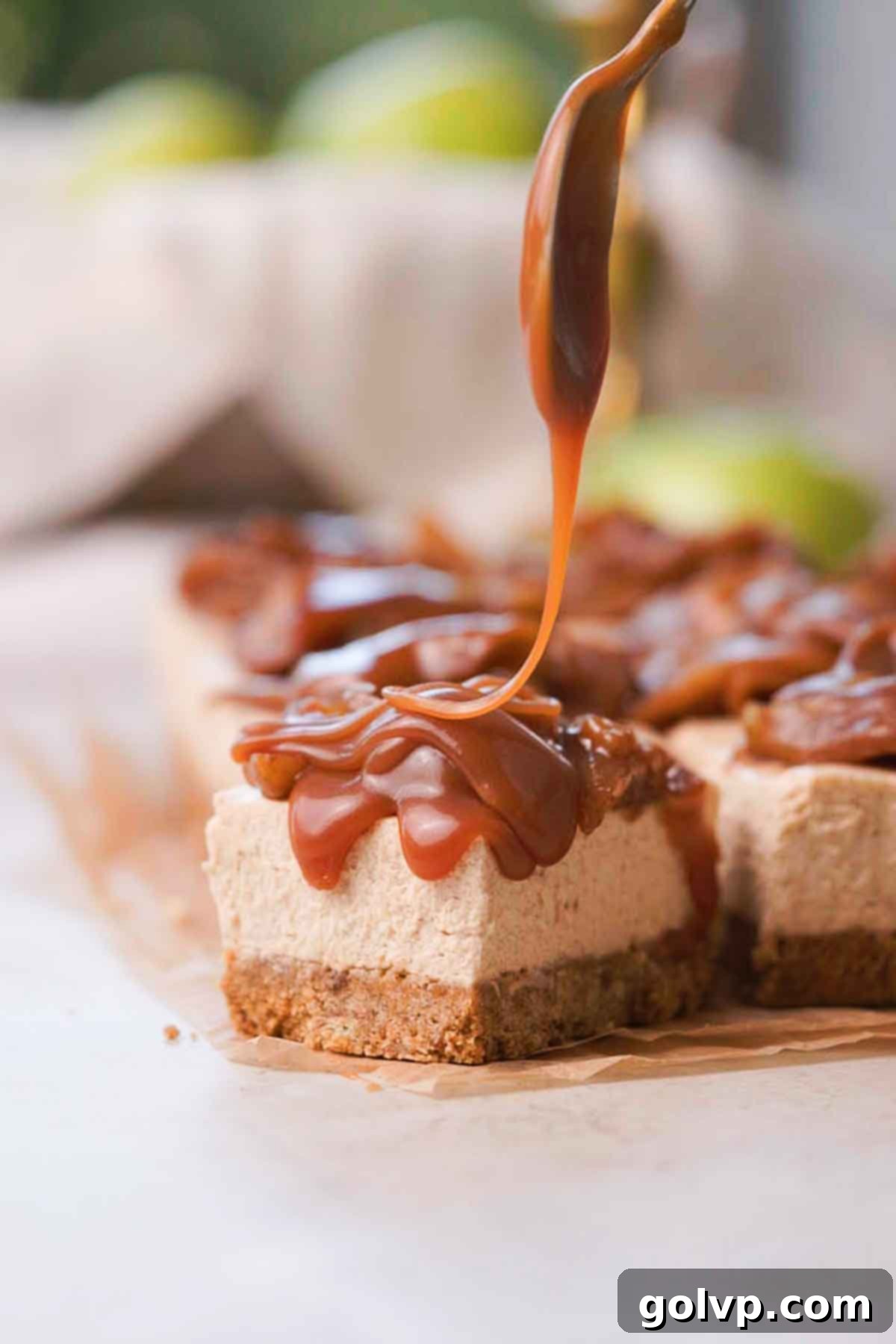 spooning caramel sauce onto cheesecake bar