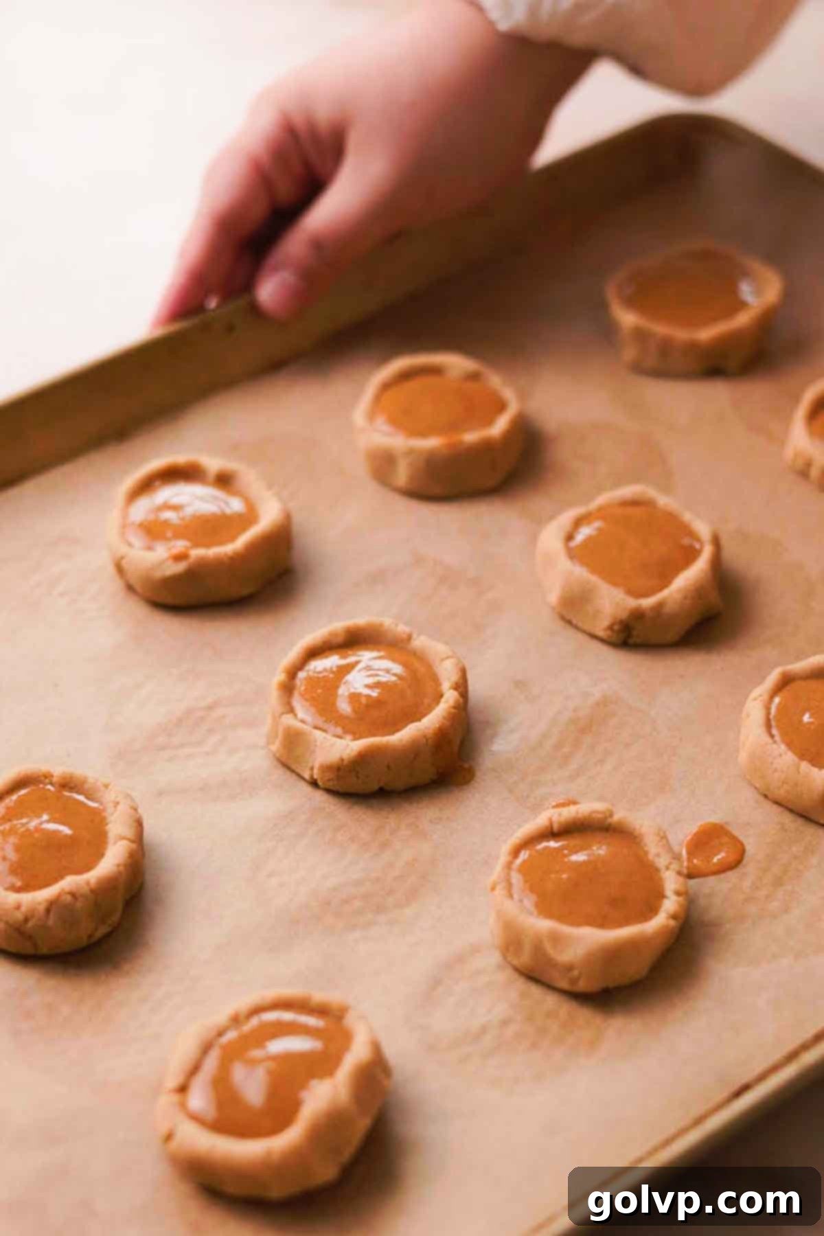 Chilled cookie dough on a baking sheet, filled with pumpkin pie filling and ready to bake.