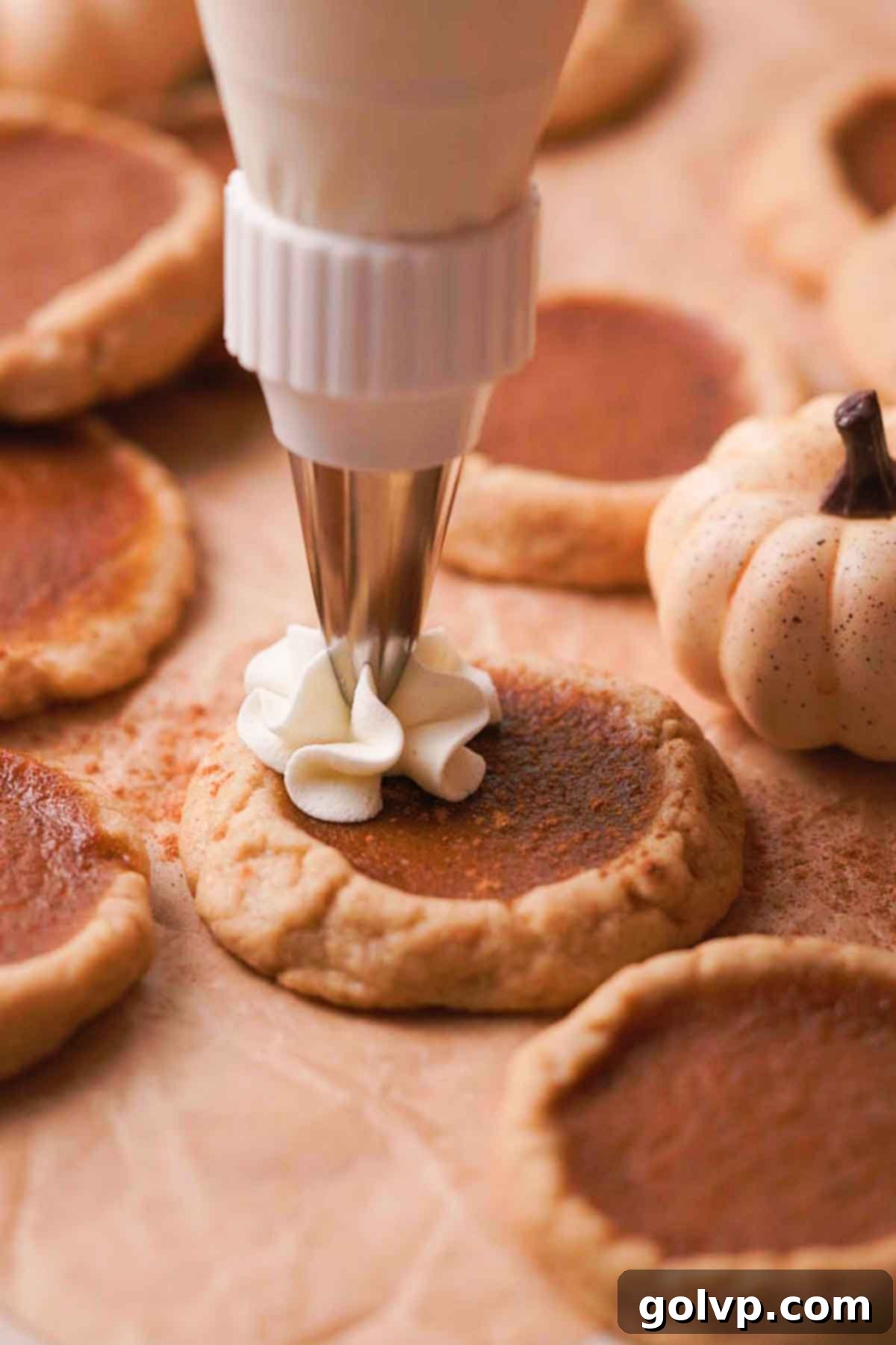 Piping a dollop of fluffy whipped cream onto a cooled pumpkin pie cookie as a final garnish.