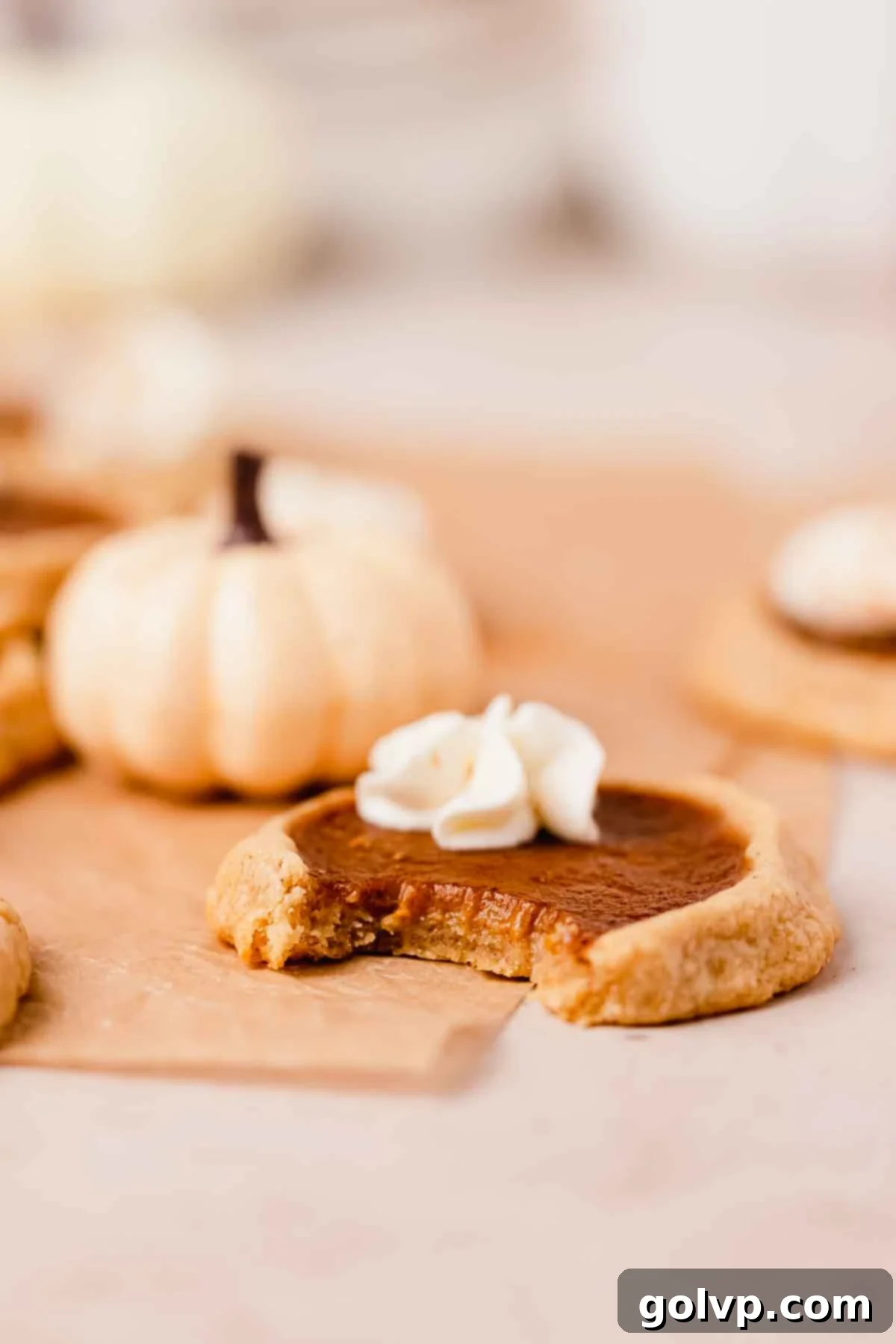 Closeup of a pumpkin pie cookie with a bite taken out, showcasing the creamy pumpkin filling and shortbread crust.