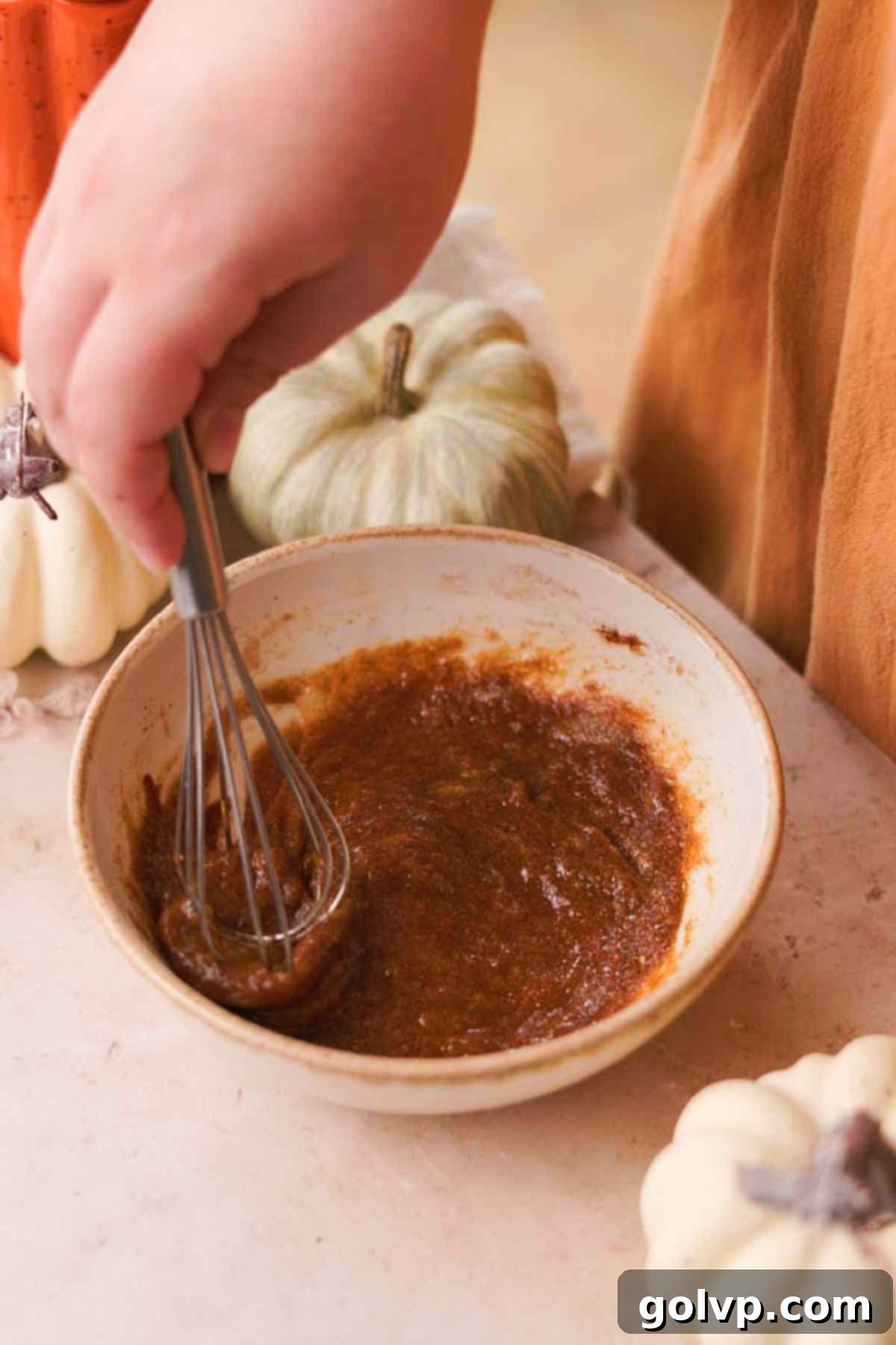Whisking together a large egg and brown sugar in a bowl for the pumpkin pie filling.