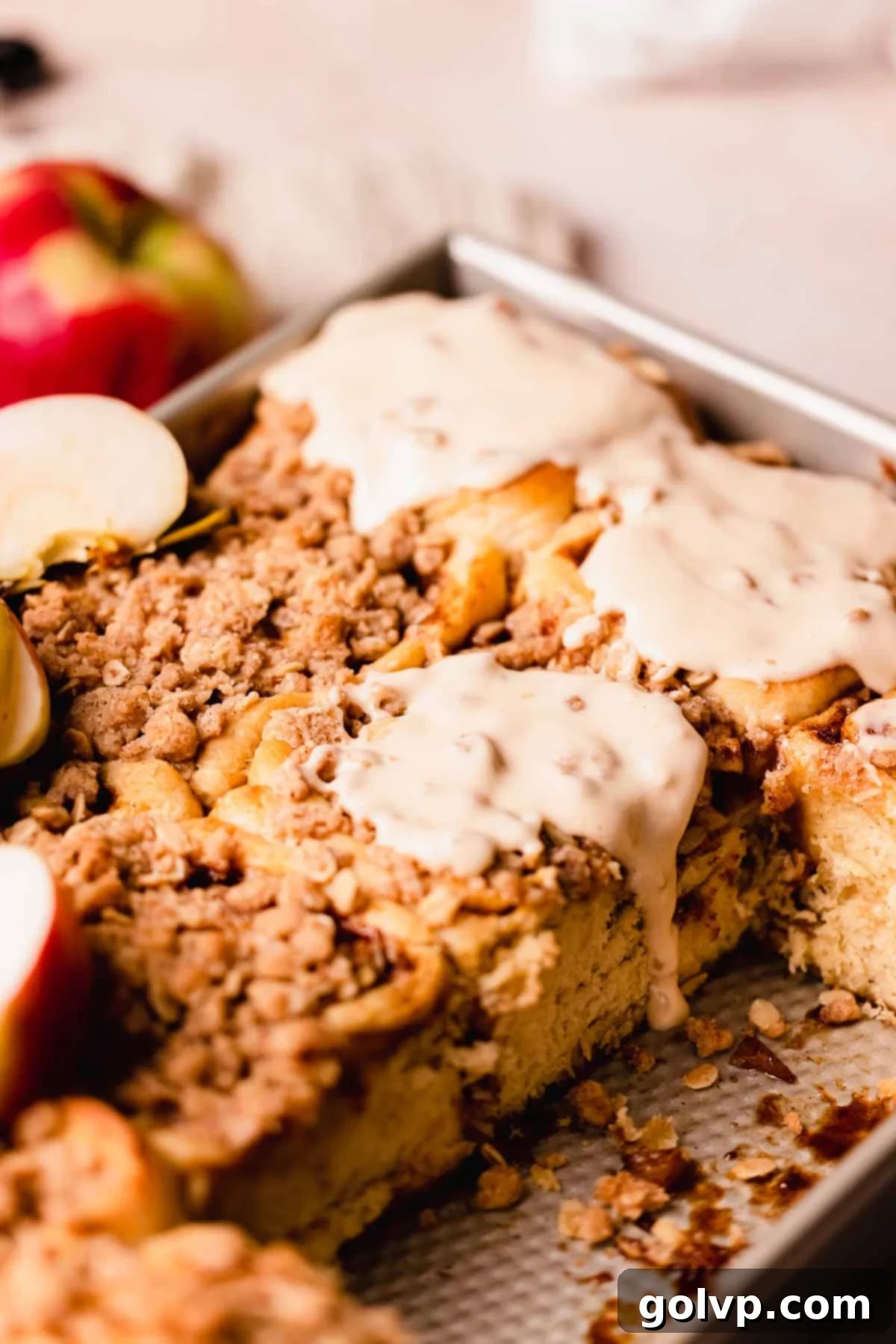 Delicious caramel apple pie cinnamon roll with a generous swirl of salted caramel cream cheese glaze and crunchy cinnamon crumble topping, ready to be enjoyed.