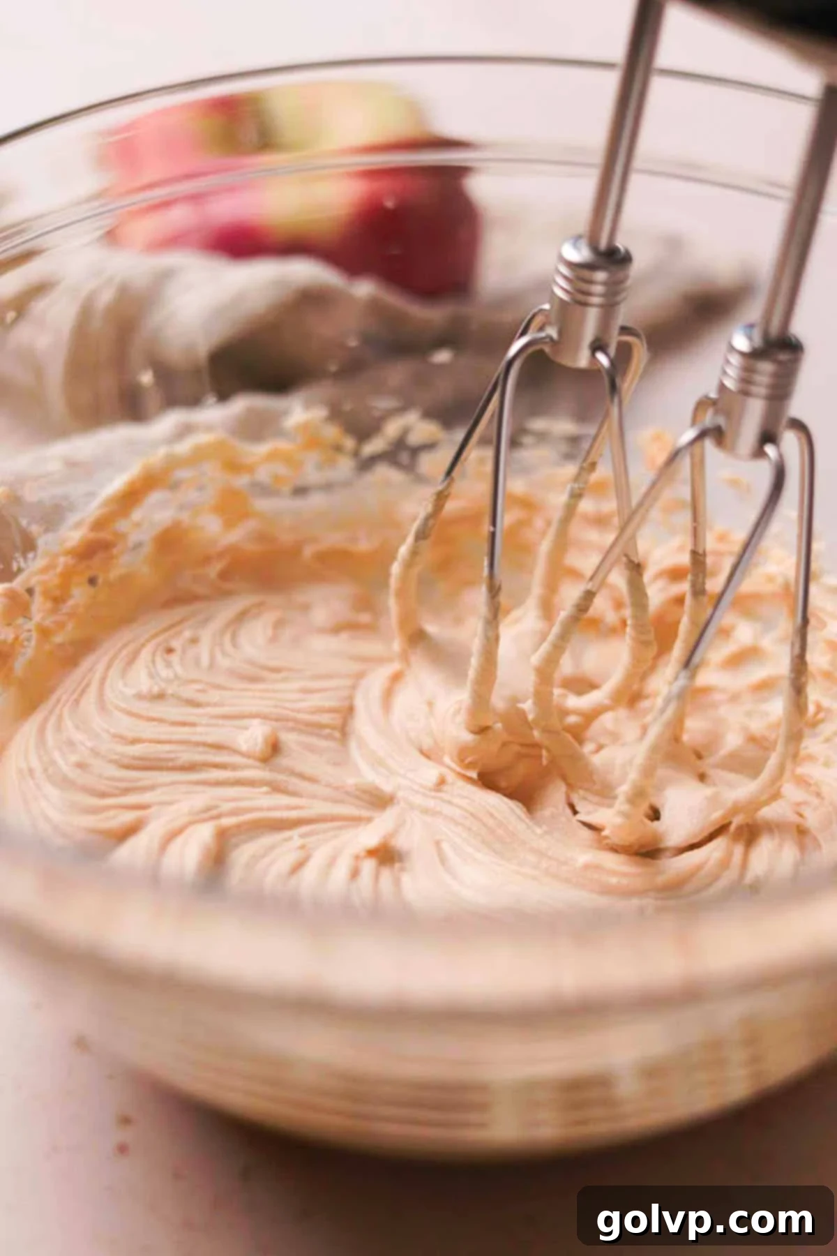 Whisking softened cream cheese and salted caramel sauce together in a bowl with an electric mixer until smooth and creamy for the glaze.