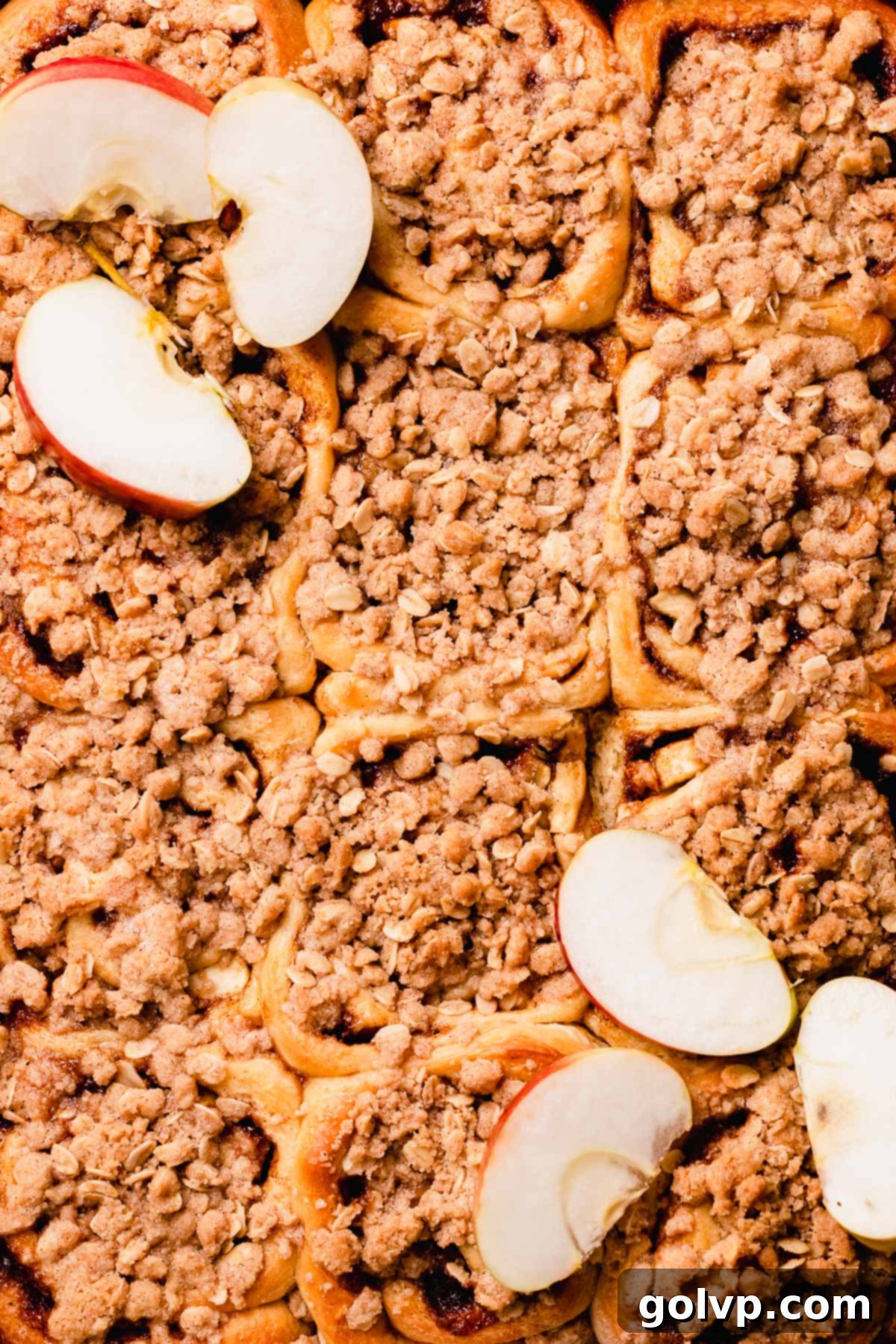 Close-up of golden-brown apple cinnamon rolls with a crisp crumble topping, freshly baked and inviting.