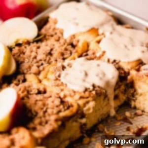 A beautifully glazed apple cinnamon roll with drips of caramel cream cheese glaze, showcasing its gooey texture.
