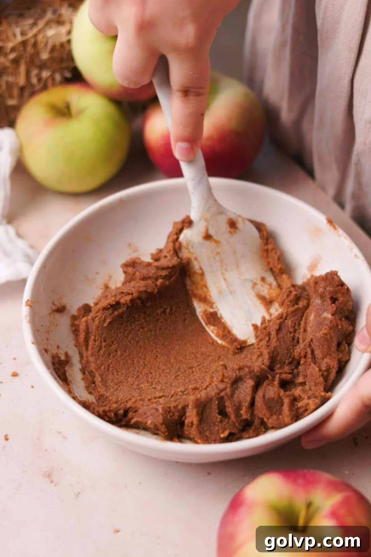 A bowl filled with a creamy, spiced cinnamon sugar butter mixture for the apple cinnamon roll filling.