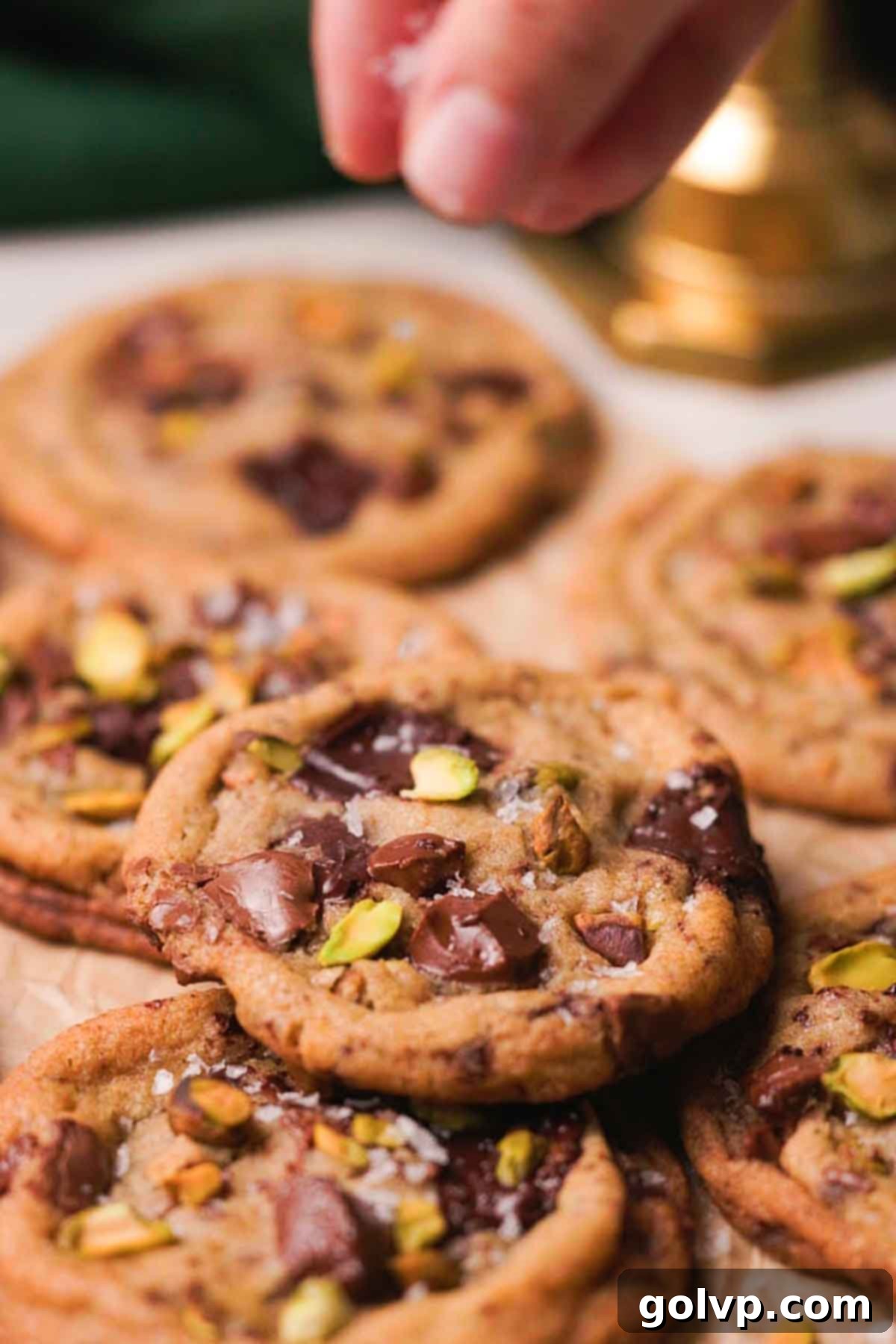 sprinkling flaky salt over pistachio chocolate cookies