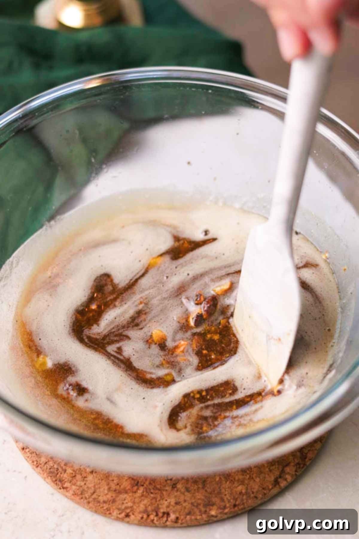 stirring brown butter with pistachios in a glass bowl