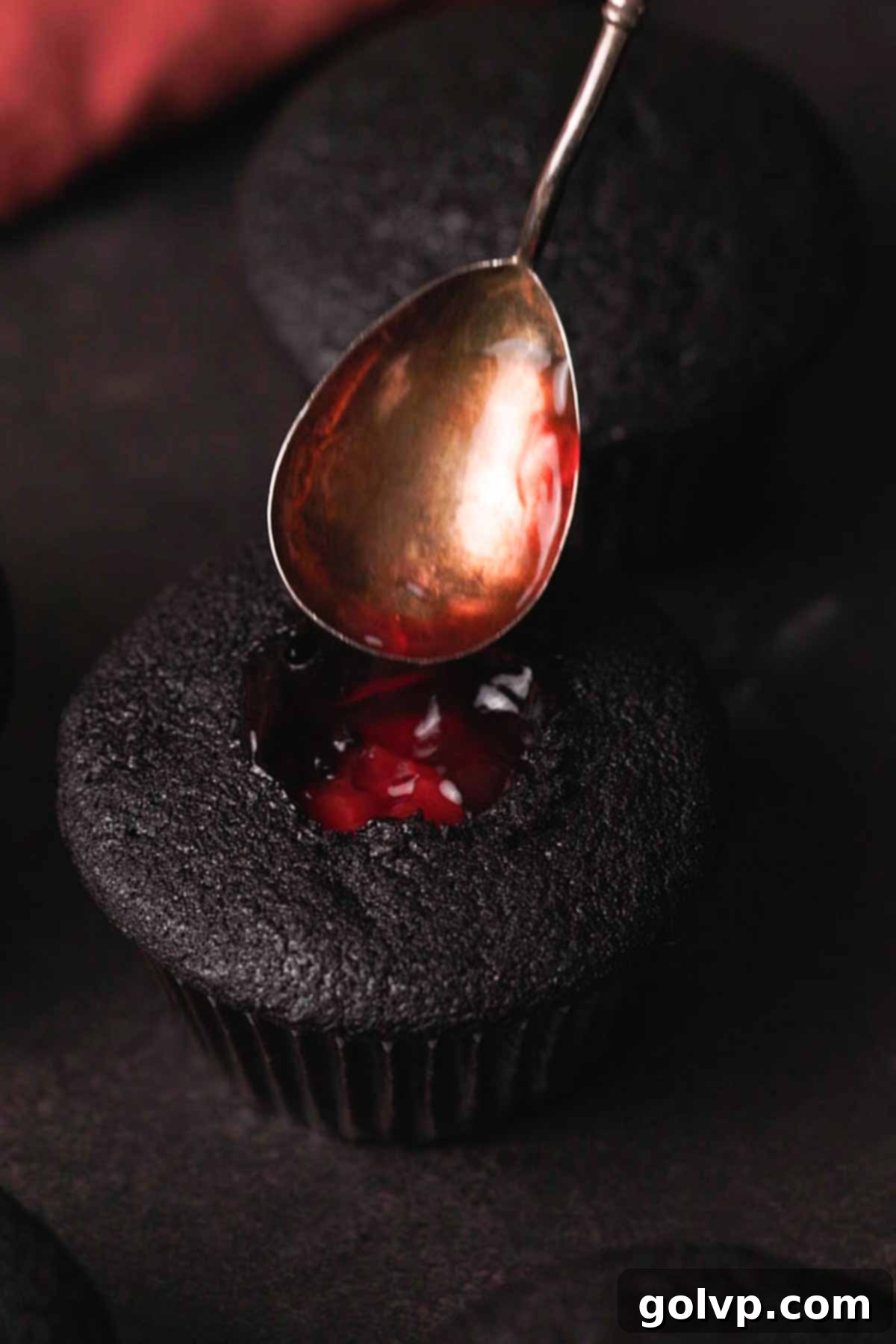 filling center of cupcake with vibrant cherry pie filling