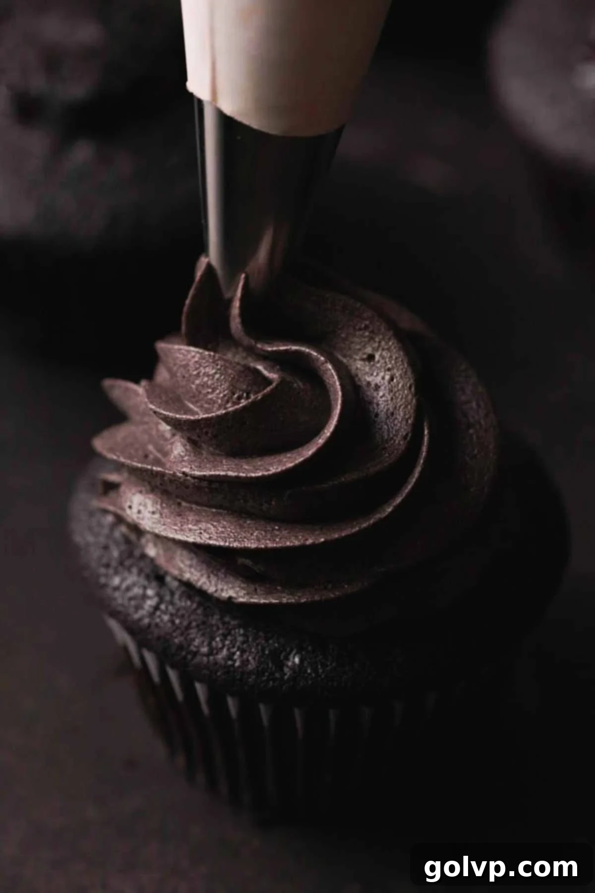 Dark Chocolate Fudge Cookies 14 piping black frosting onto cupcake